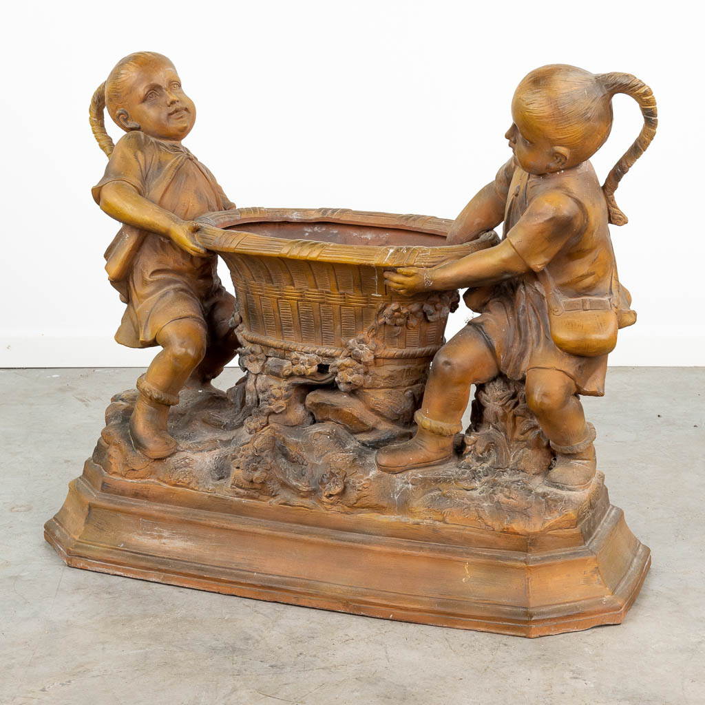 A large terracotta statue of two children and a basket, made of terracotta and marked 