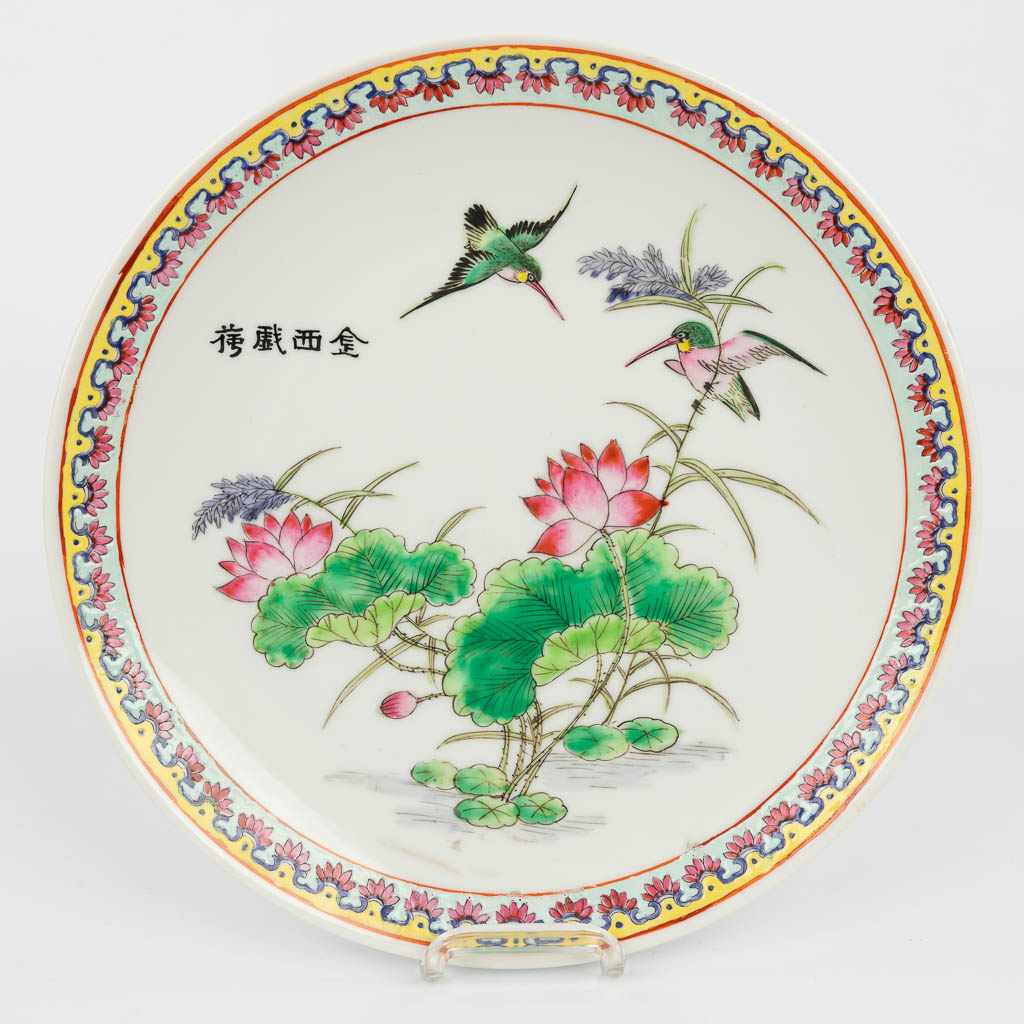 A pair of Chinese plates made of porcelain and decorated with fauna and flora. 20th century. Marked Qianlong. 