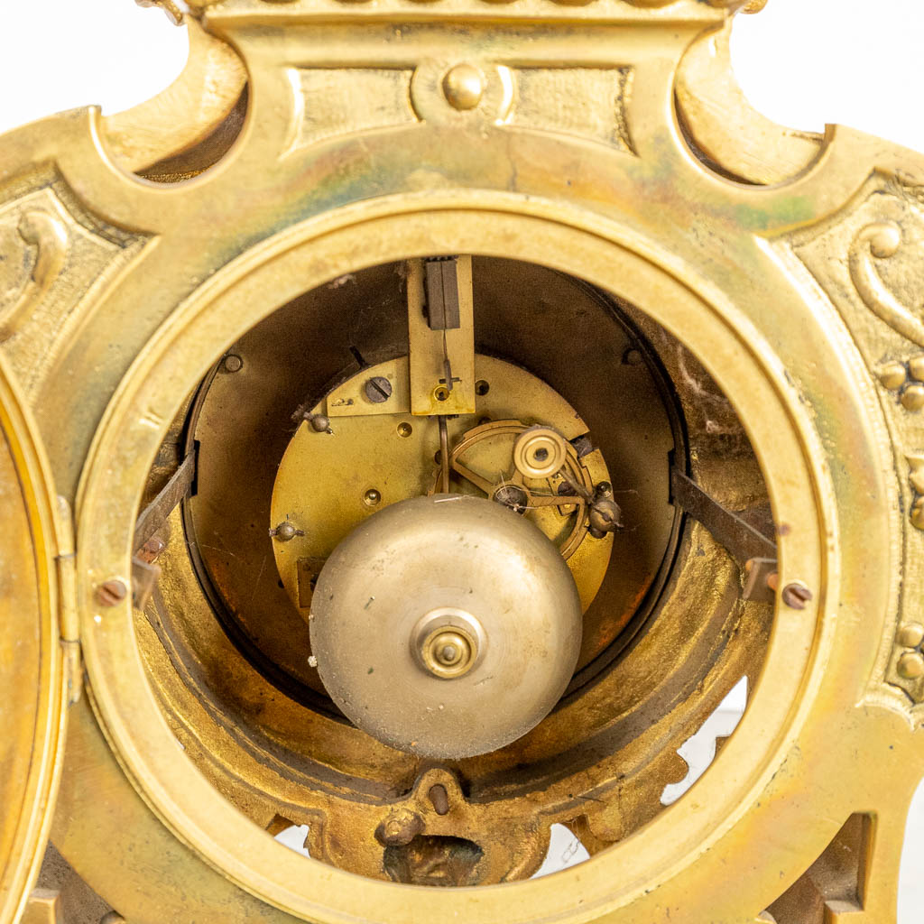 Een driedelige schouwgarnituur gemaakt uit brons bestaande uit een klok met twee kandelaars. (H:70cm)