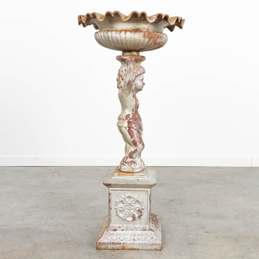 A garden vase made of cast iron and decorated with a putto. (H:84cm)