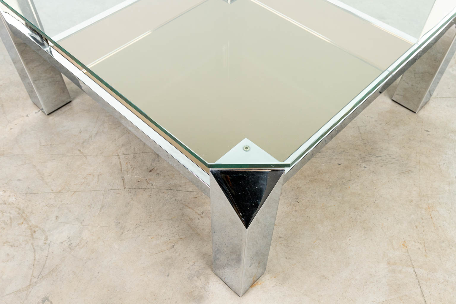 A coffee table made of chome-plated metal with fumé and clear glass.