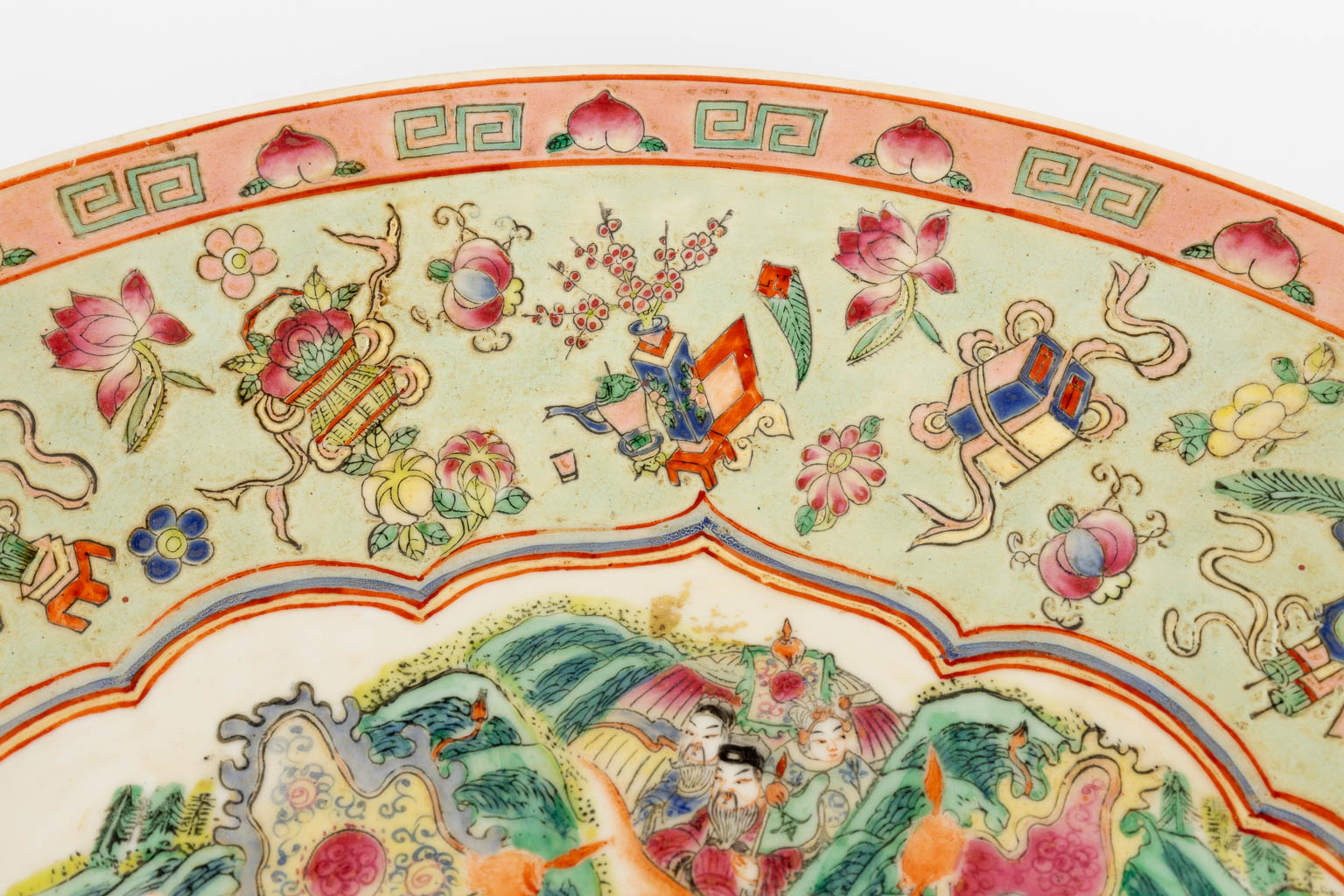 Een Chinees Famille Rose sierbord, decor van krijgers, perzikken en antiquiteiten. 19de/20ste eeuw. (D:45,5 cm)