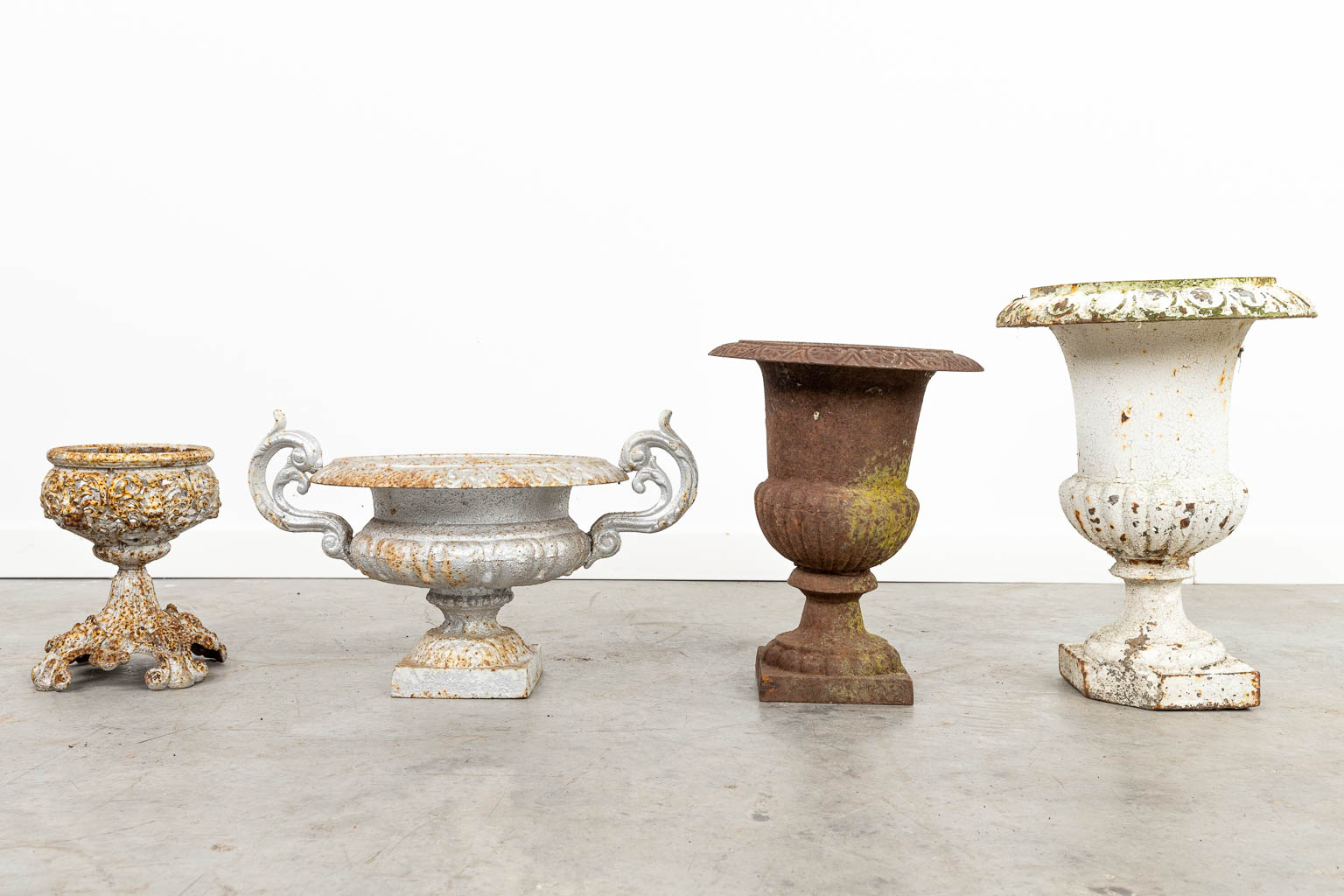 A collection of 7 different garden vases made of cast iron. 