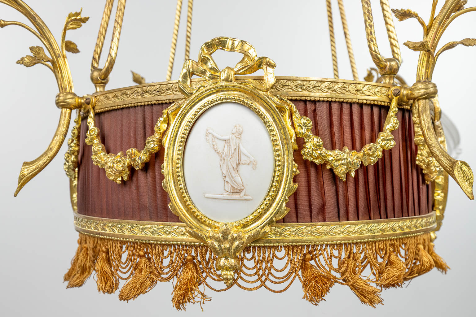 A chandelier made of bronze in Louis XVI style and finished with bisque plaques. (H:100cm)