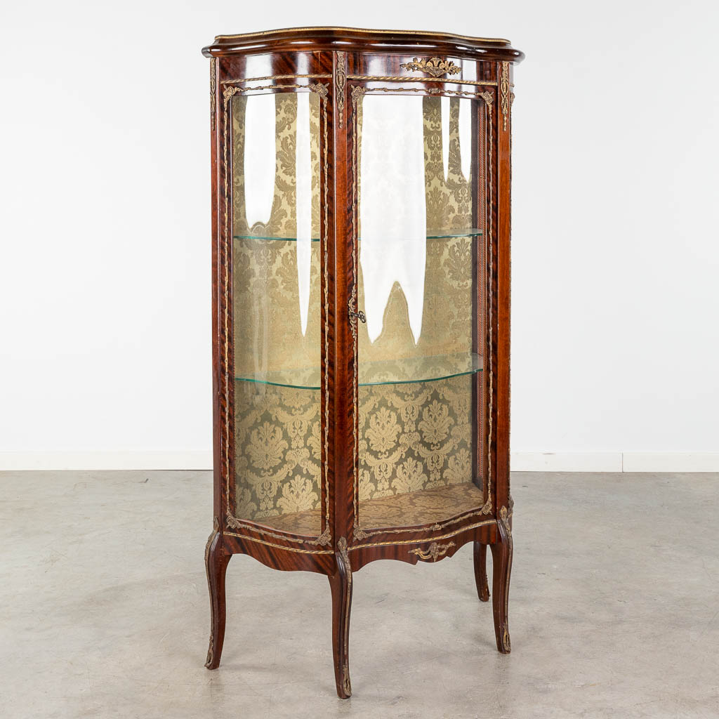  Een vintage vitrinekast afgewerkt met gebogen glas en brons in Lodewijk XV stijl.
