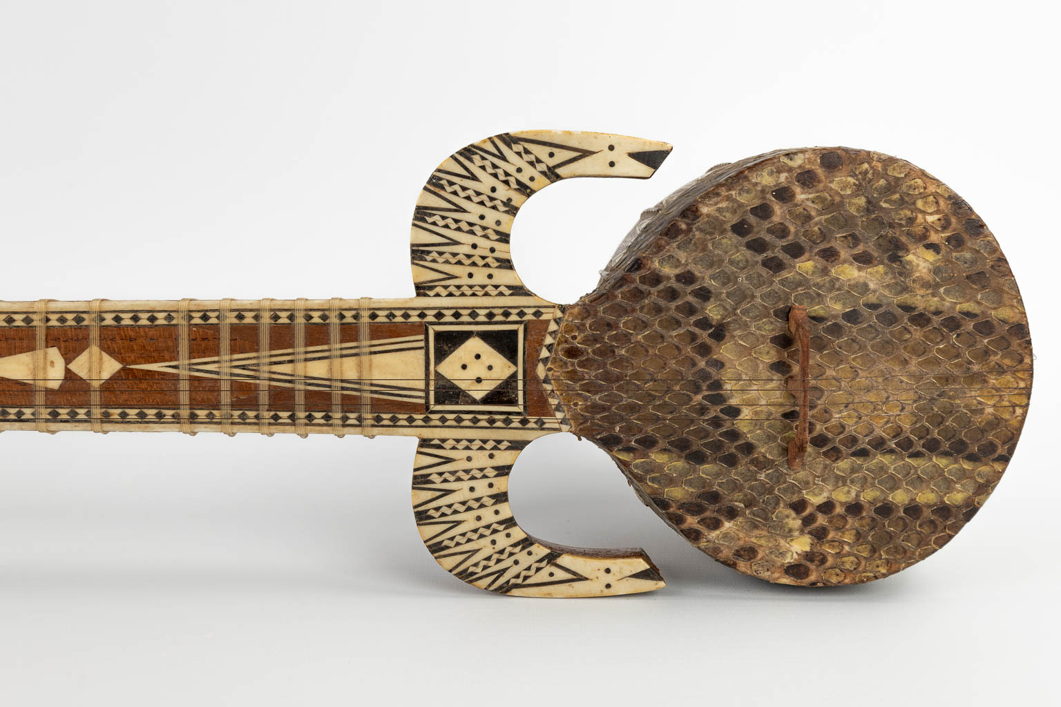 An oriental musical instrument with 6 strings, snake leather and bone inlay. 20th C. (D:13 x W:15 x H:93 cm)