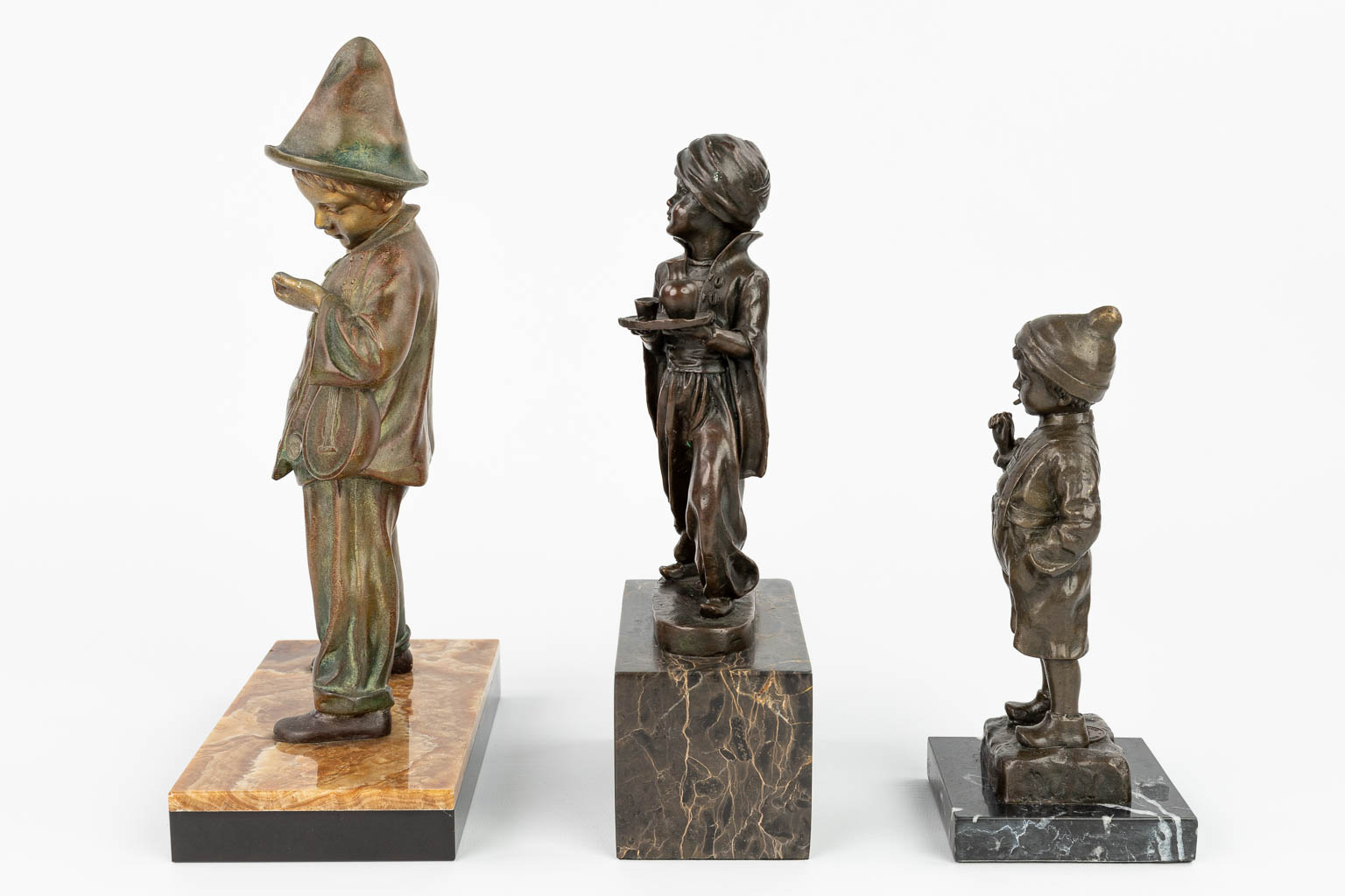 Een collectie van 3 beelden van jongens gemaakt uit brons en kunstbrons. (H:30,5cm)
