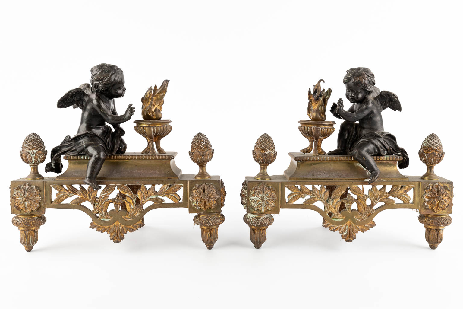 A pair of bronze fireplace andirons, gilt and patinated bronze, Louis XVI style. Circa 1900. (W:30 x H:27 cm)