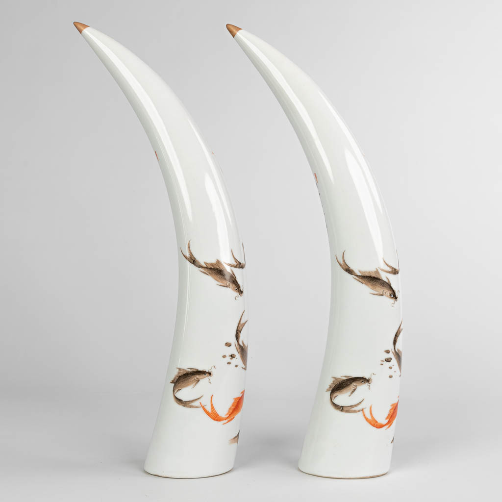 A pair of tusks, made of Chinese porcelain and decorated with fish.