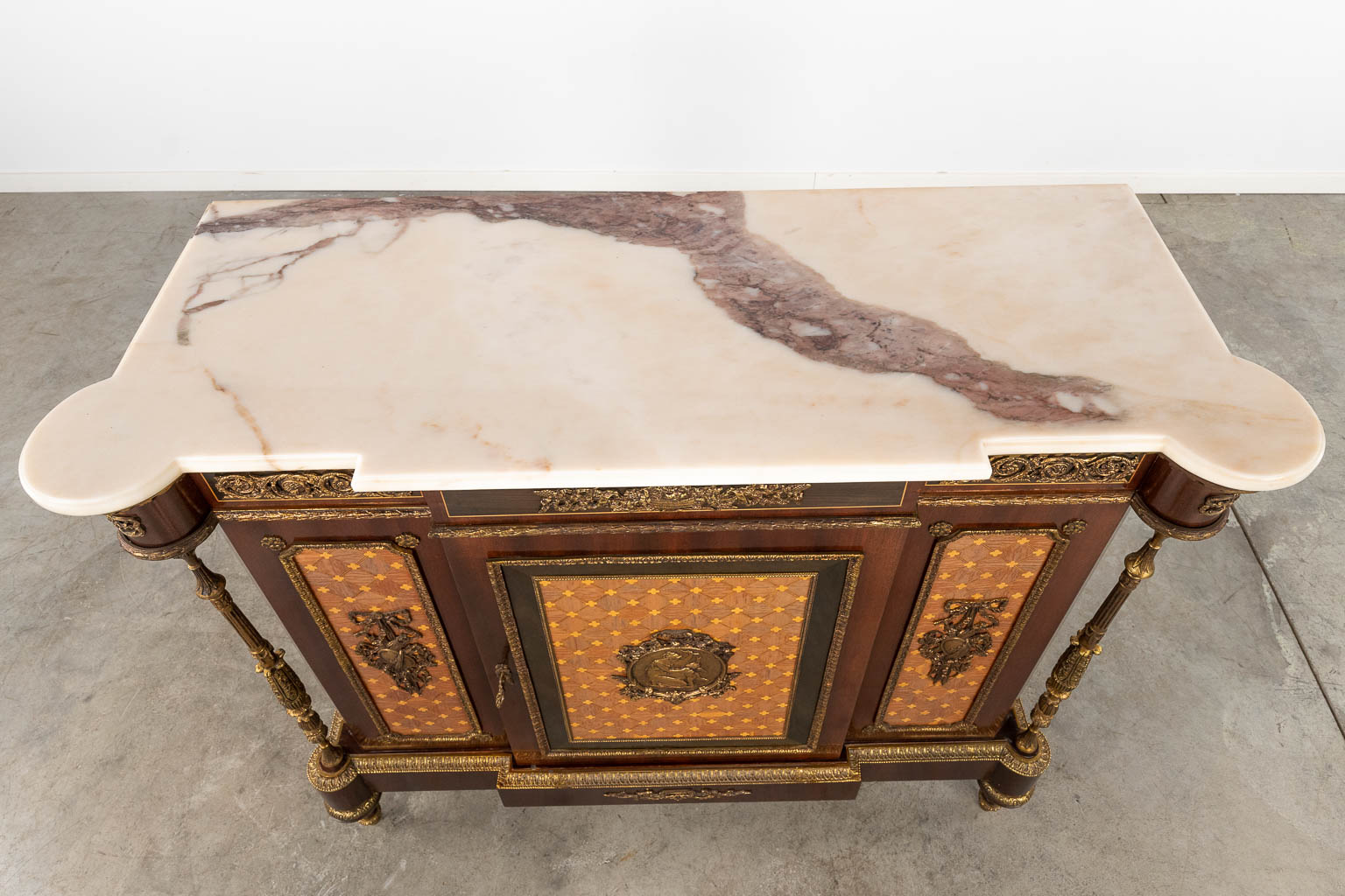 A cabinet, wood veneer mounted with bronze in Louis XVI style with a marble top. 20th C. (D:44 x W:120 x H:106 cm)