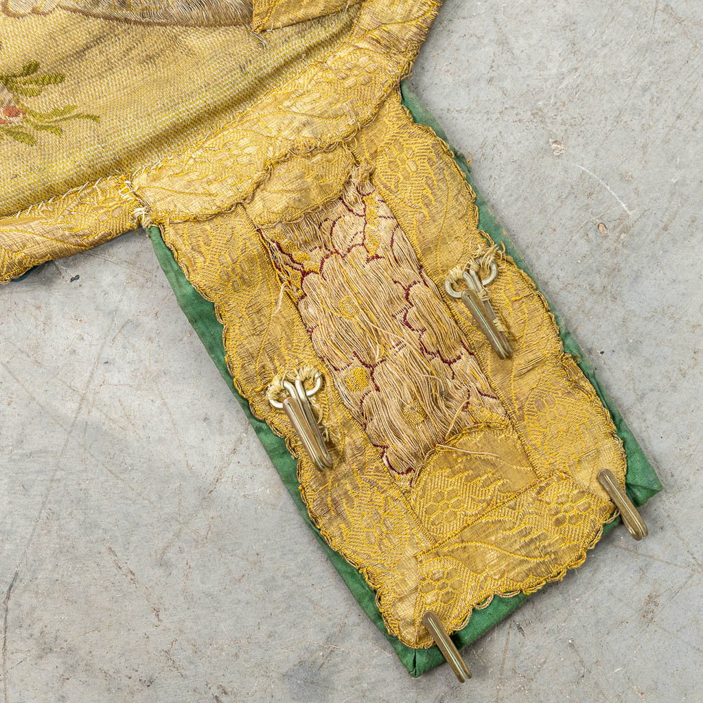 Een koorkap - koormantel versierd met bloemen en een witte duif, afgewerkt met geborduurd gouddraad. (H:128cm)