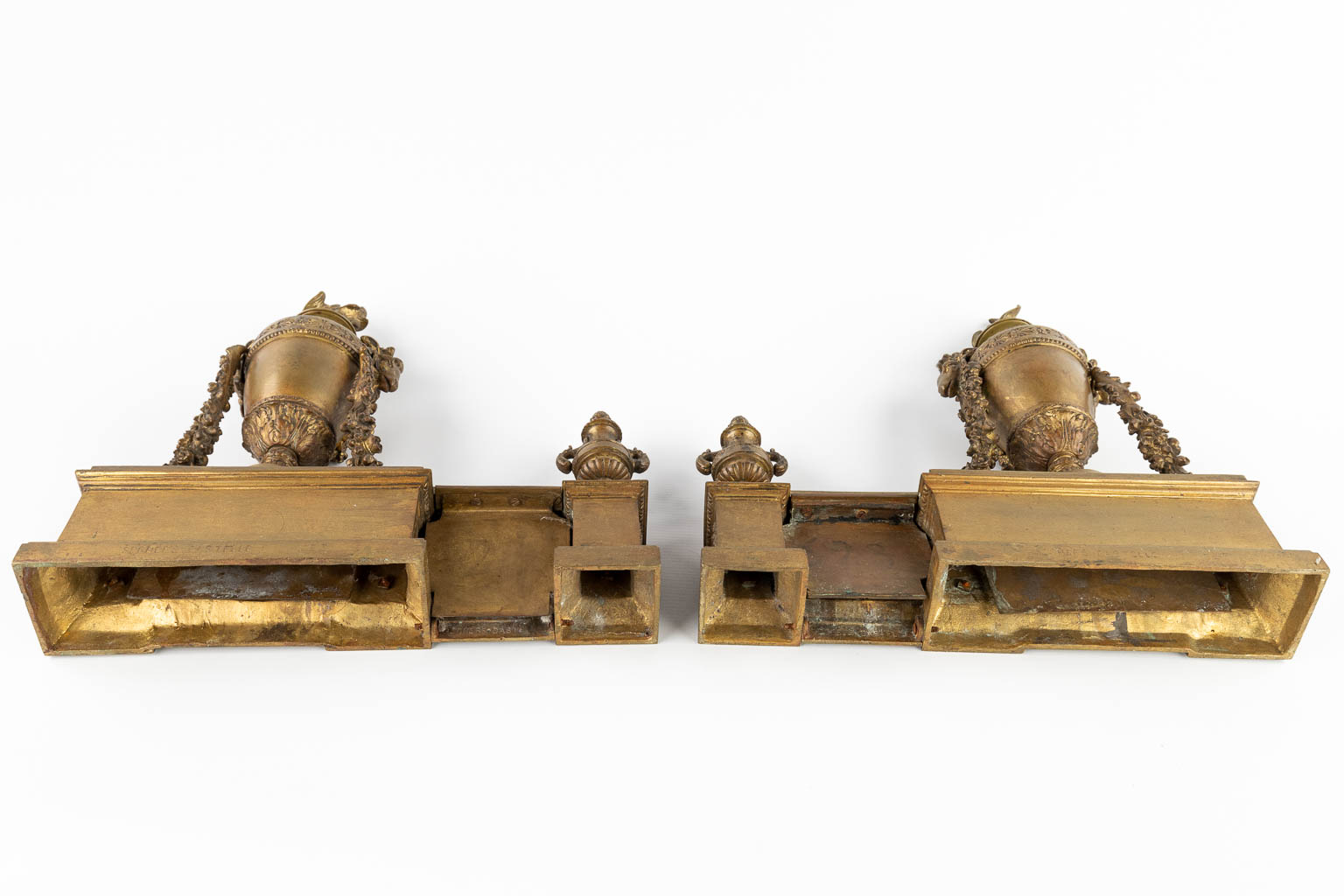 Een paar haardvuurbokken, brons in Lodewijk XVI stijl en afgewerkt met ramskoppen. (D:10 x W:37 x H:37 cm)