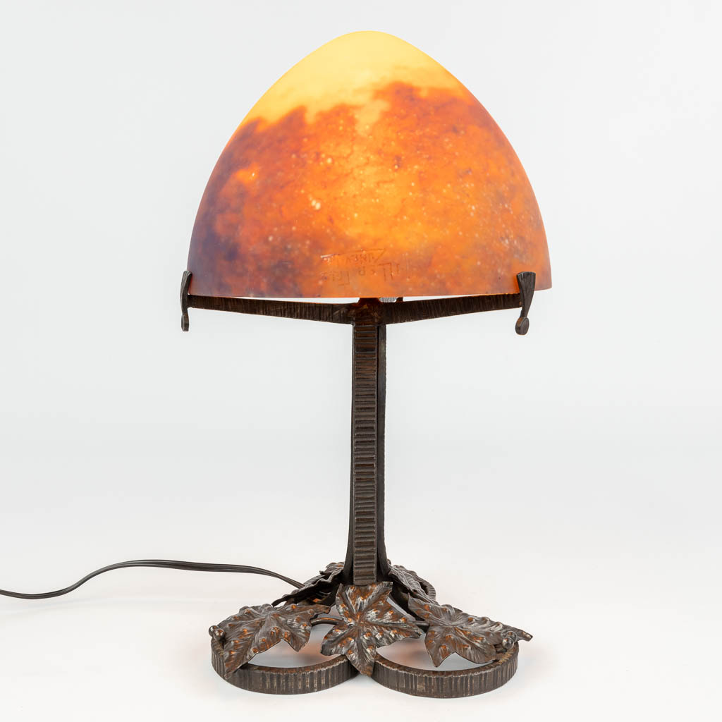 Een smeedijzeren tafellamp met pâte de verre lampenkap getekend Muller Frêres Lunéville. (H:39 x D:22 cm)
