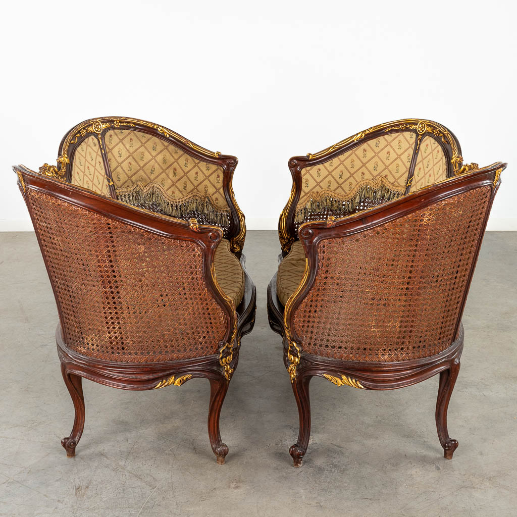 Een paar zetels, gesculpteerd hout in Lodewijk XV stijl, afgwerkt met gevlochten riet. (D:62 x W:115 x H:84 cm)