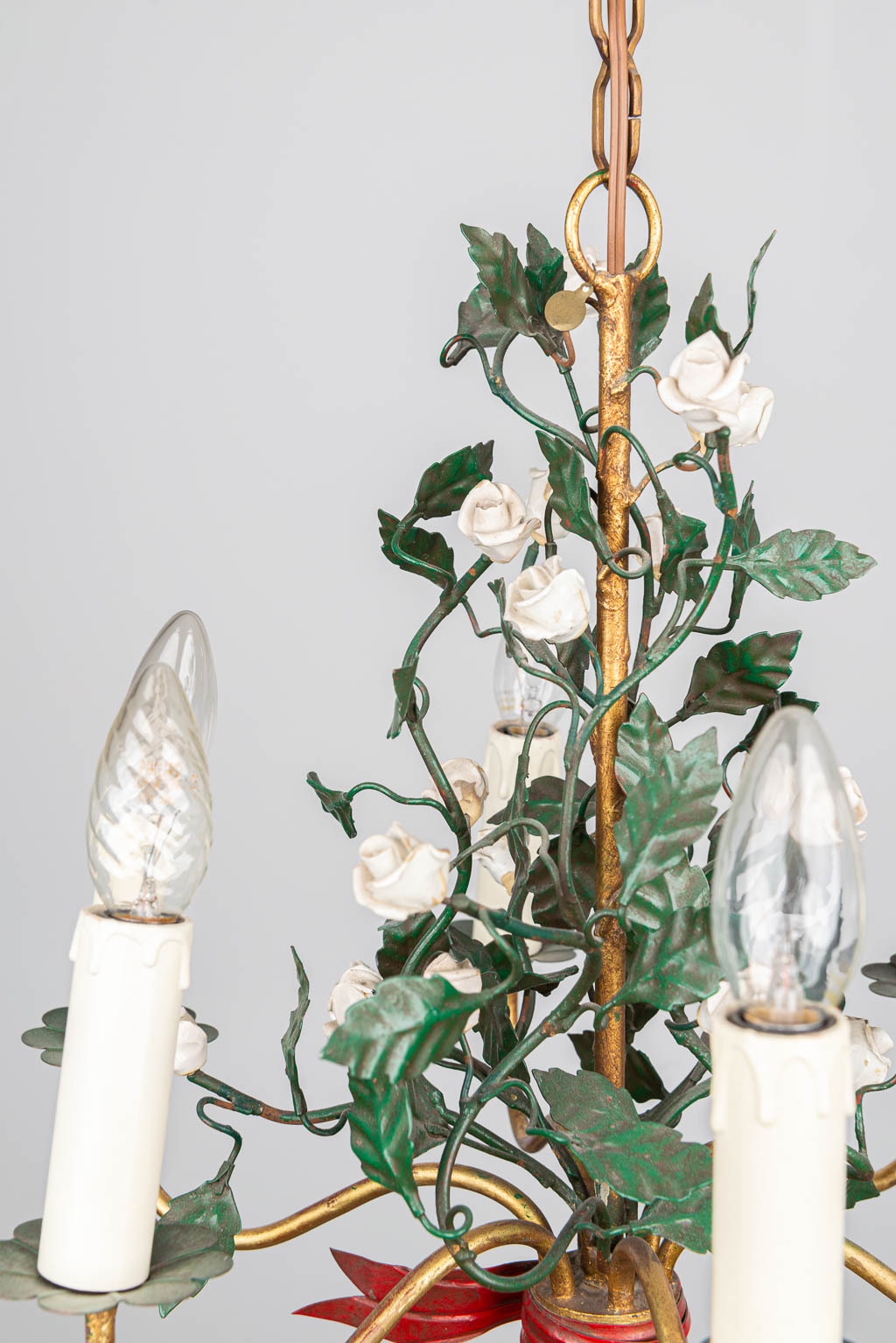 Een luchter gemaakt uit metaal en versierd met bloemen gemaakt uit porselein. 