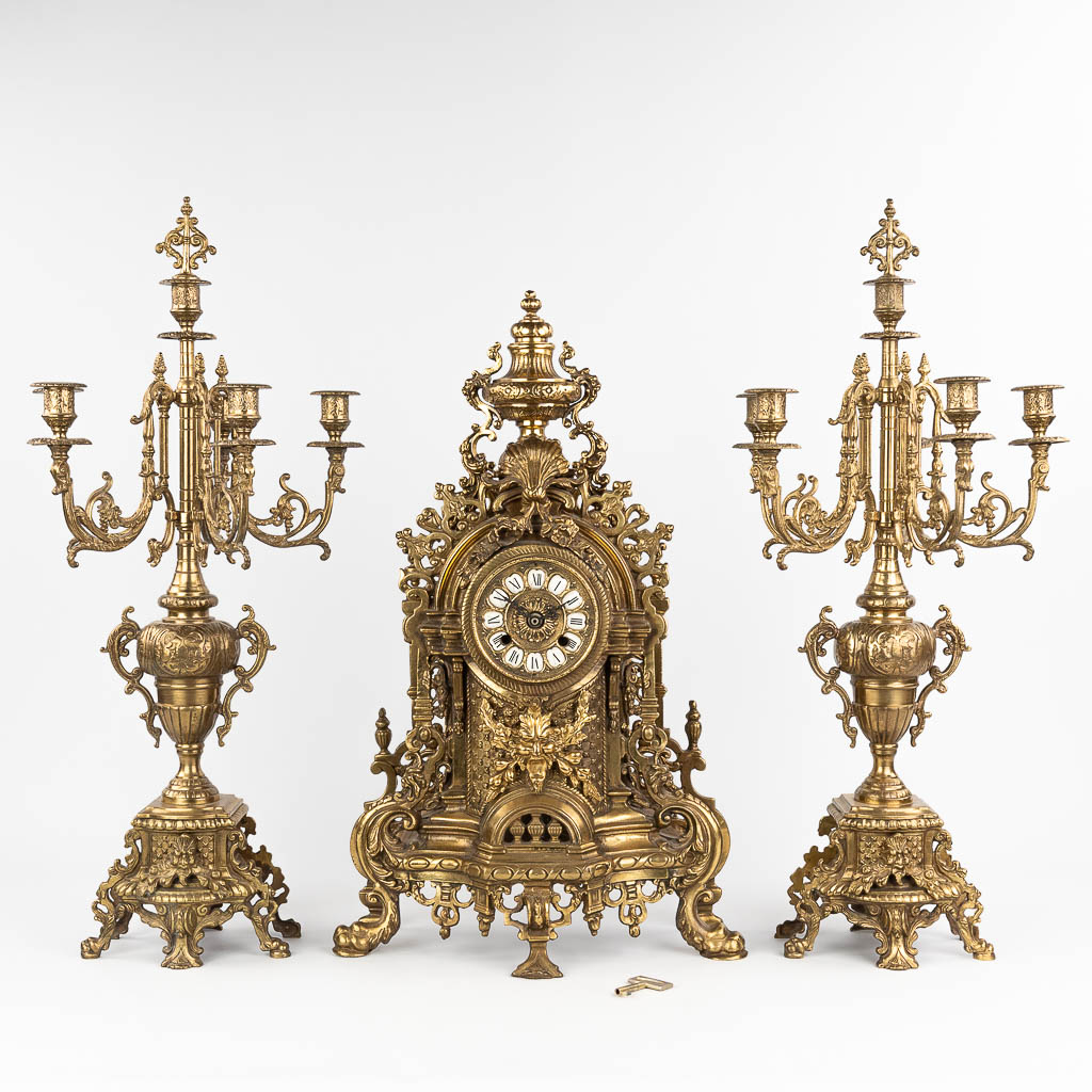  A three-piece mantle garniture consisting of a clock with candelabra, made of bronze. circa 1970.
