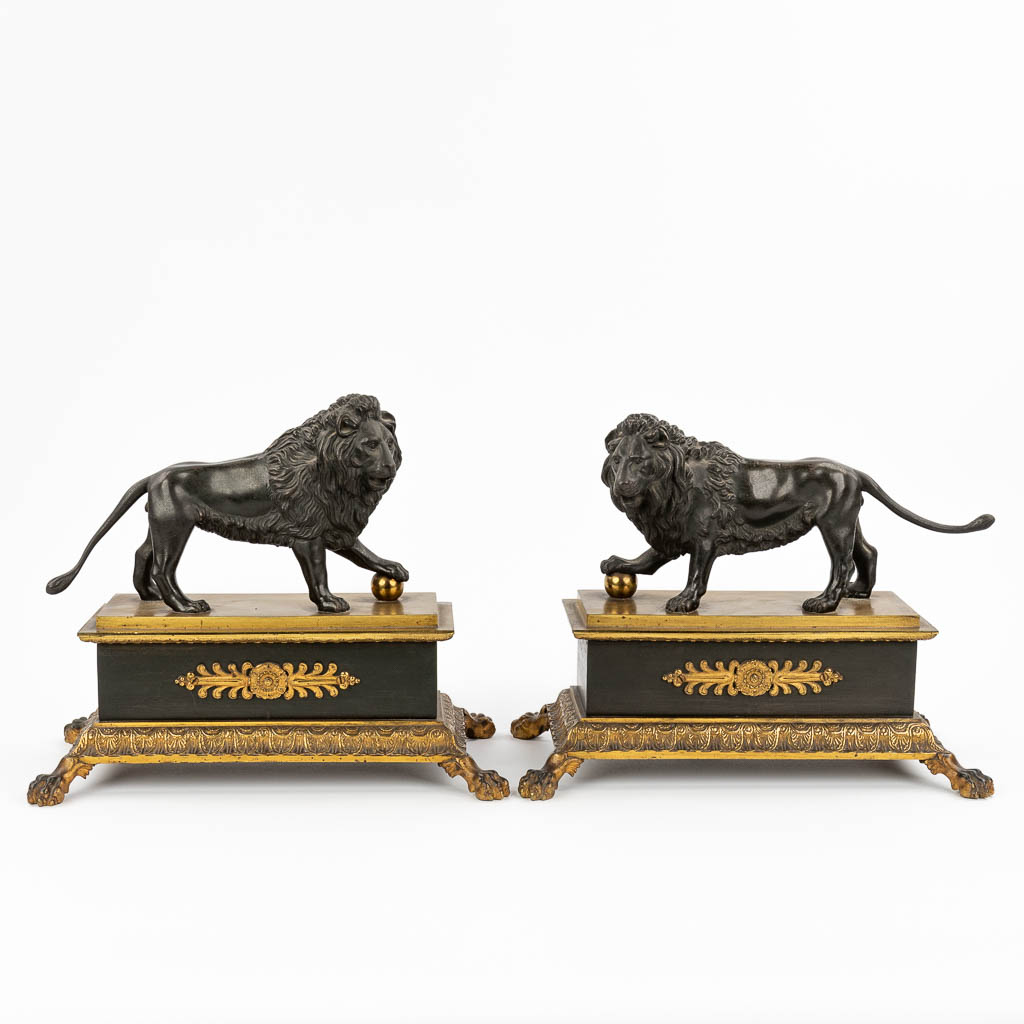 Een paar leeuwen op een sokkel, gemaakt uit gepatineerd en verguld brons in empire stijl. (L: 17,5 x W: 32 x H: 26 cm)