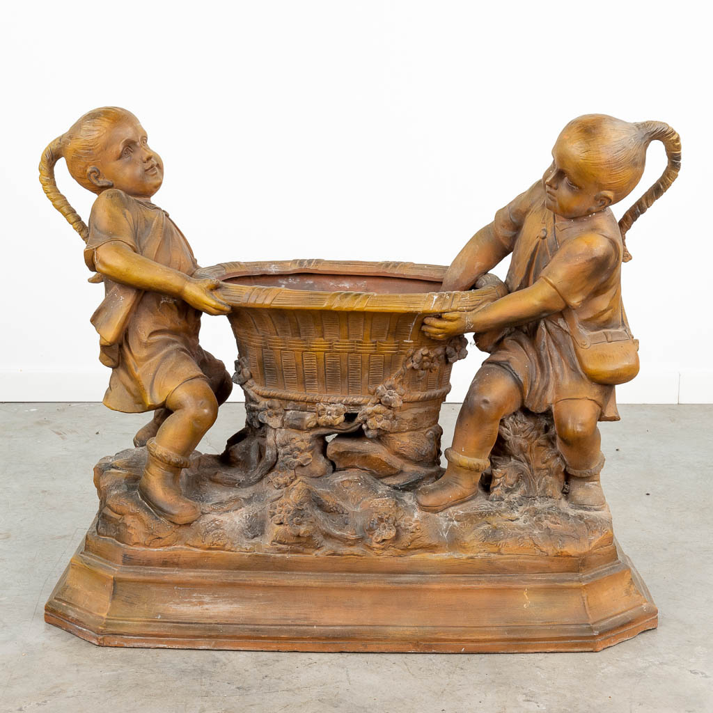 Een groot terracotta beeld van twee kinderen met een mand, gemerkt 