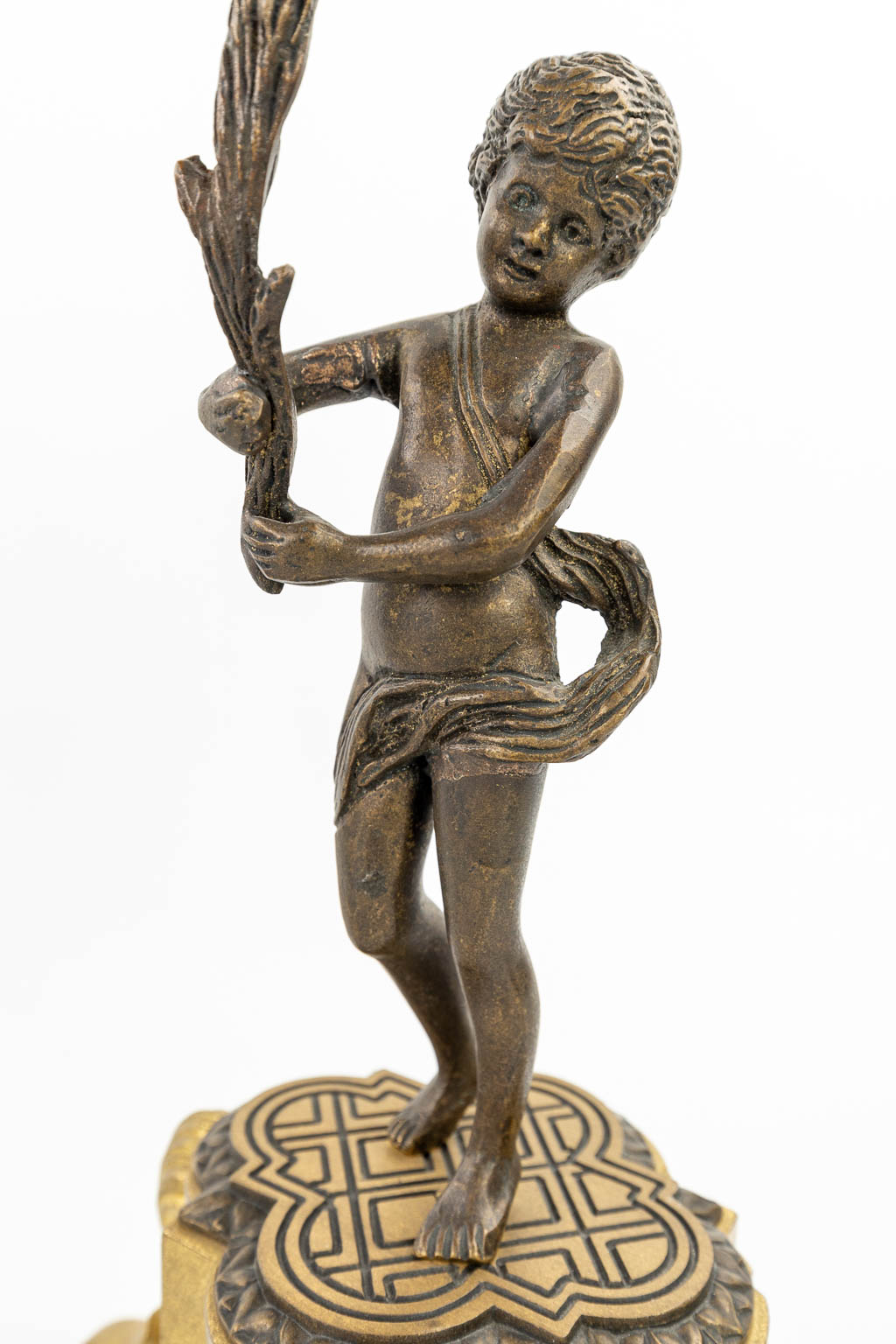 Een driedelige schouwgarnituur gemaakt uit verguld en gepolijst brons, versierd met putti. (H:46cm)