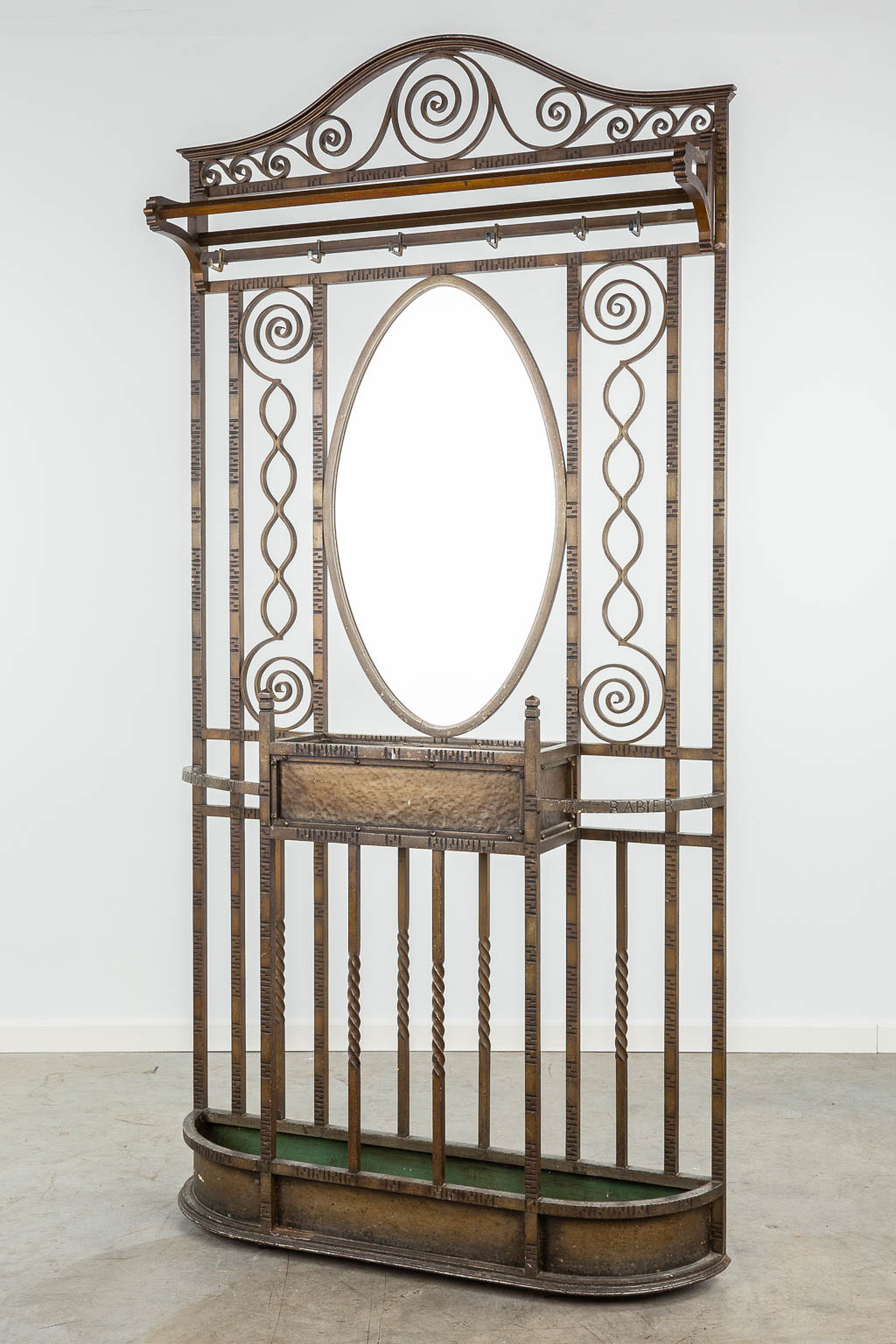 A coathanger and umbrella stand with mirror made of wrought iron and marked Victor Rabier. (H:208cm)