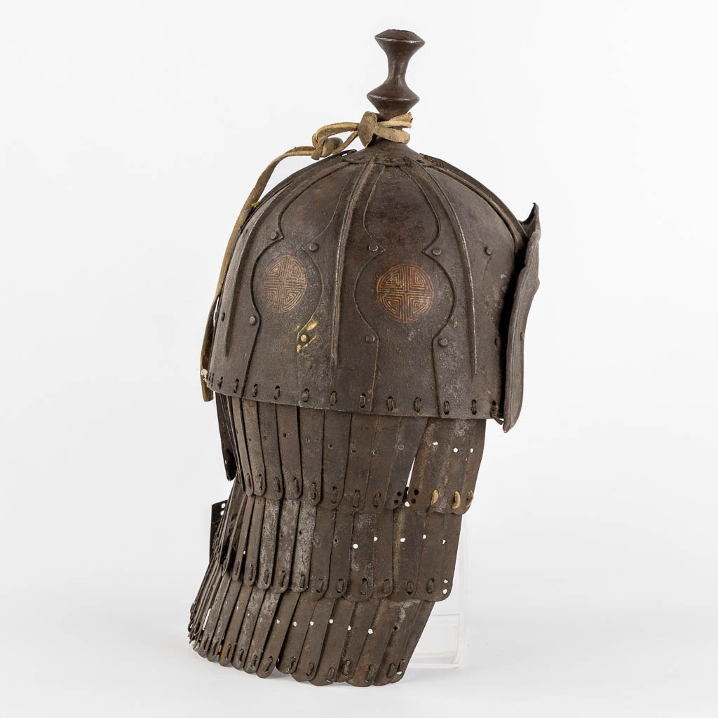 Een Tibetaanse militaire helm, metaal en leder. 18de/19de eeuw. (L:20 x W:24 x H:42 cm)