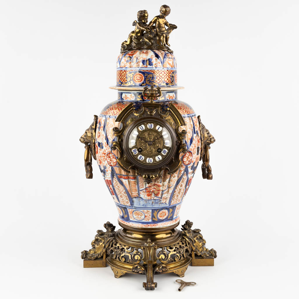 A mantle clock, Japanese Imari porcelain mounted with bronze and finished with lion's and children. 19th C. (D:28 x W:31 x H:58 