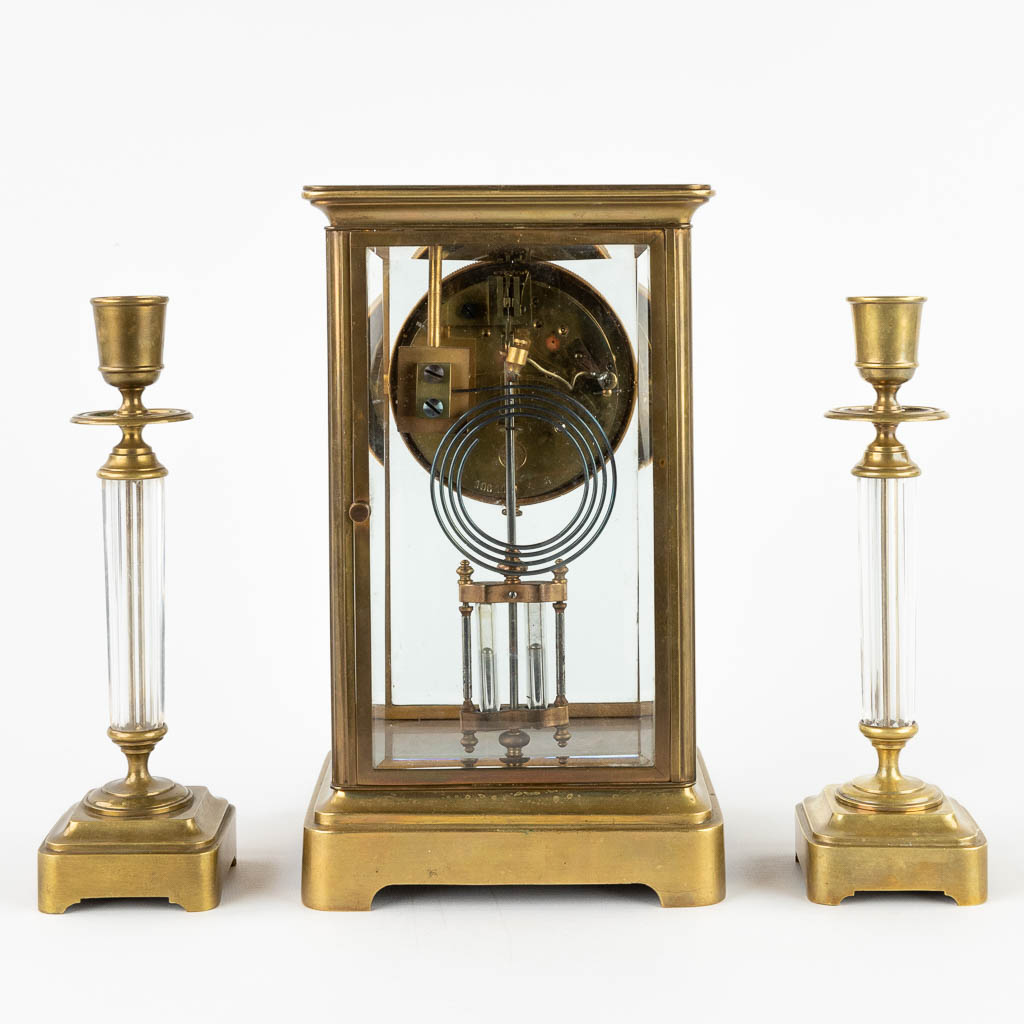 A three-piece mantle garniture clock and candlesticks. 19th C. (D:14 x W:15 x H:26 cm)