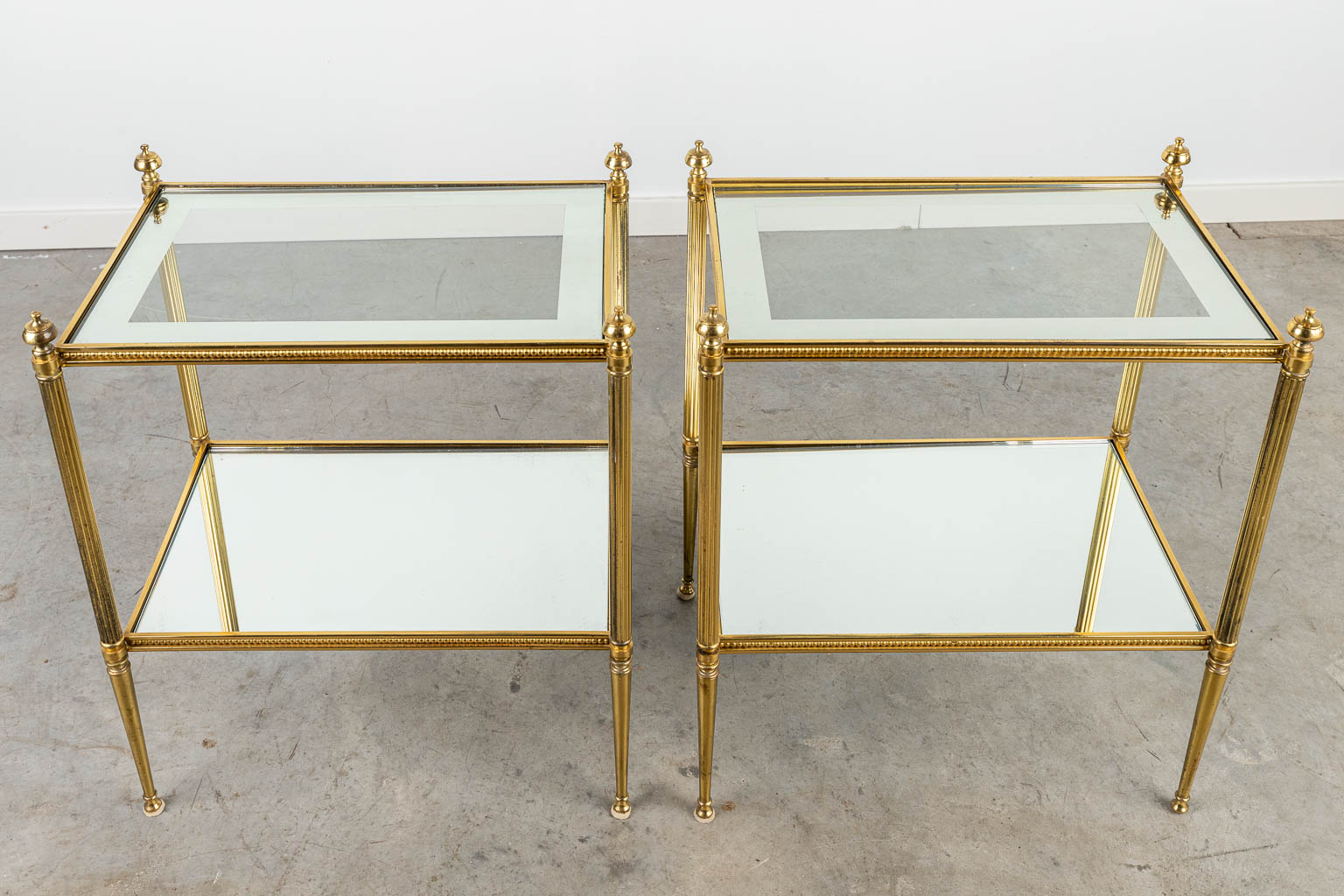 A pair of mid-century side tables made of brass and glass, in the style of Maison Jansen. (H:58cm)