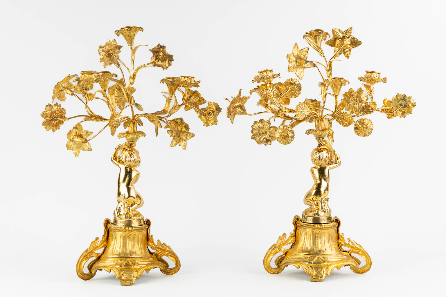 A pair of candelabra, gilt bronze decorated with putti and flowers. 19th C. (L:22 x W:36 x H:53 cm)