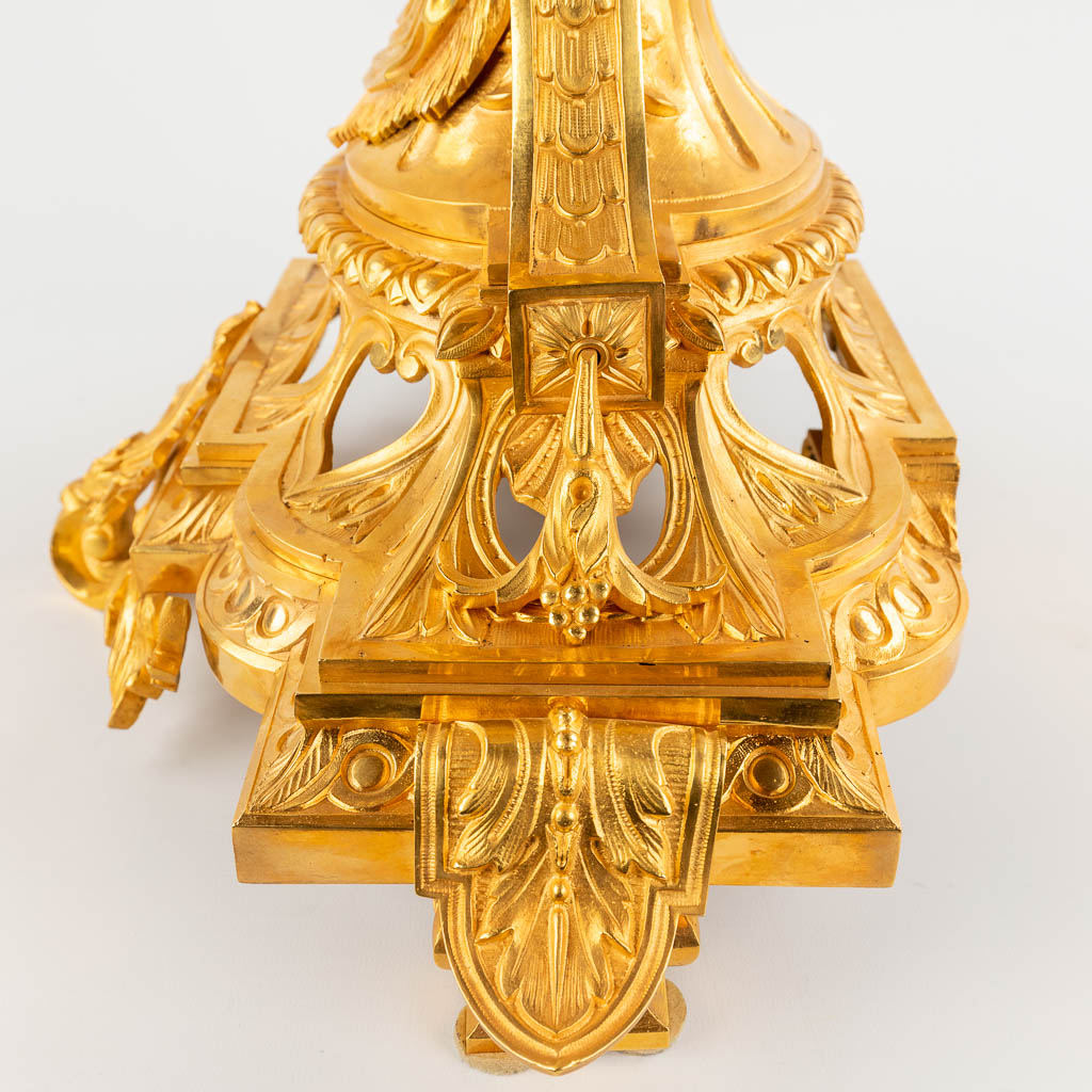 Een driedelige schouwgarnituur, klok met kandelaars, verguld brons in Lodewijk XV stijl, 19de eeuw. (D:28 x W:50 x H:61 cm)