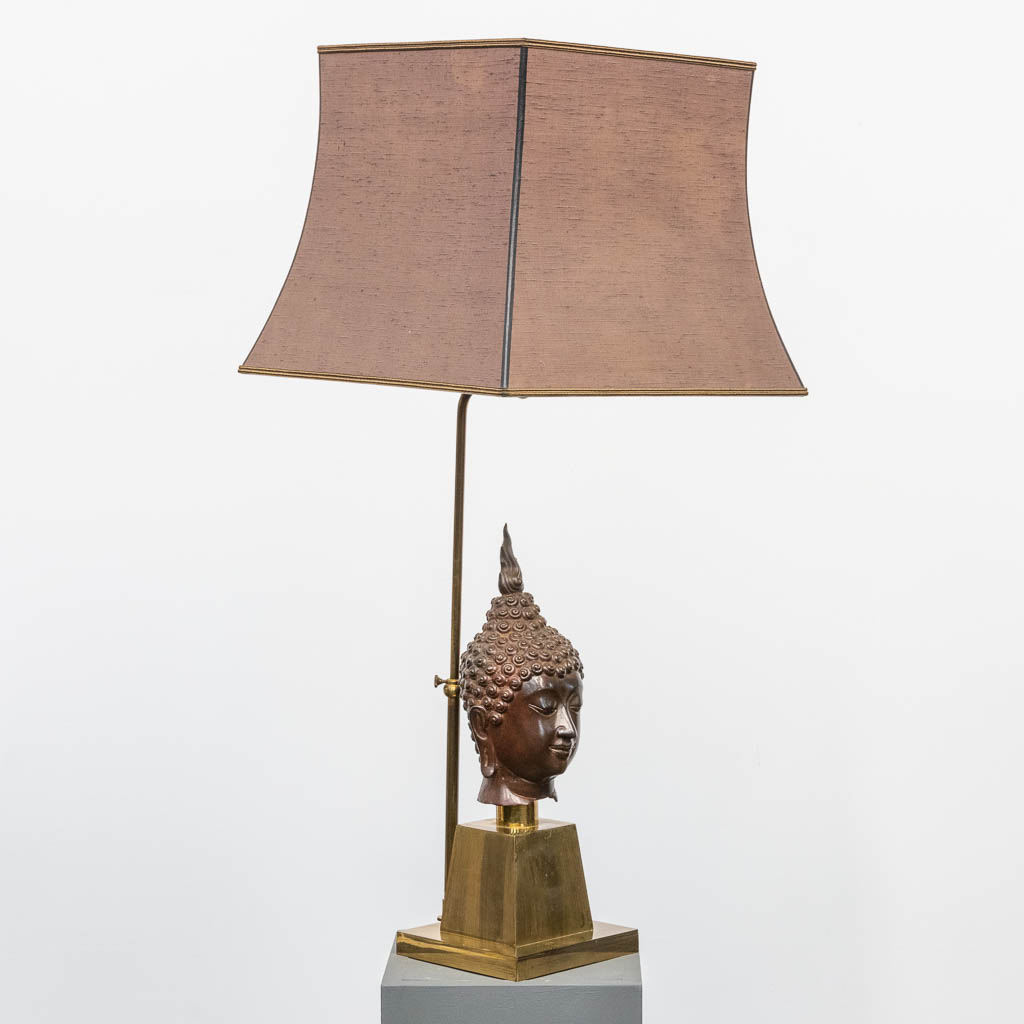 A vintage table lamp made of brass, with a bronze buddha buste. 