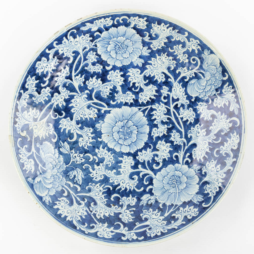 Een grote Chinese schaal gemaakt uit porselein met blauw-wit bloemendecor. 