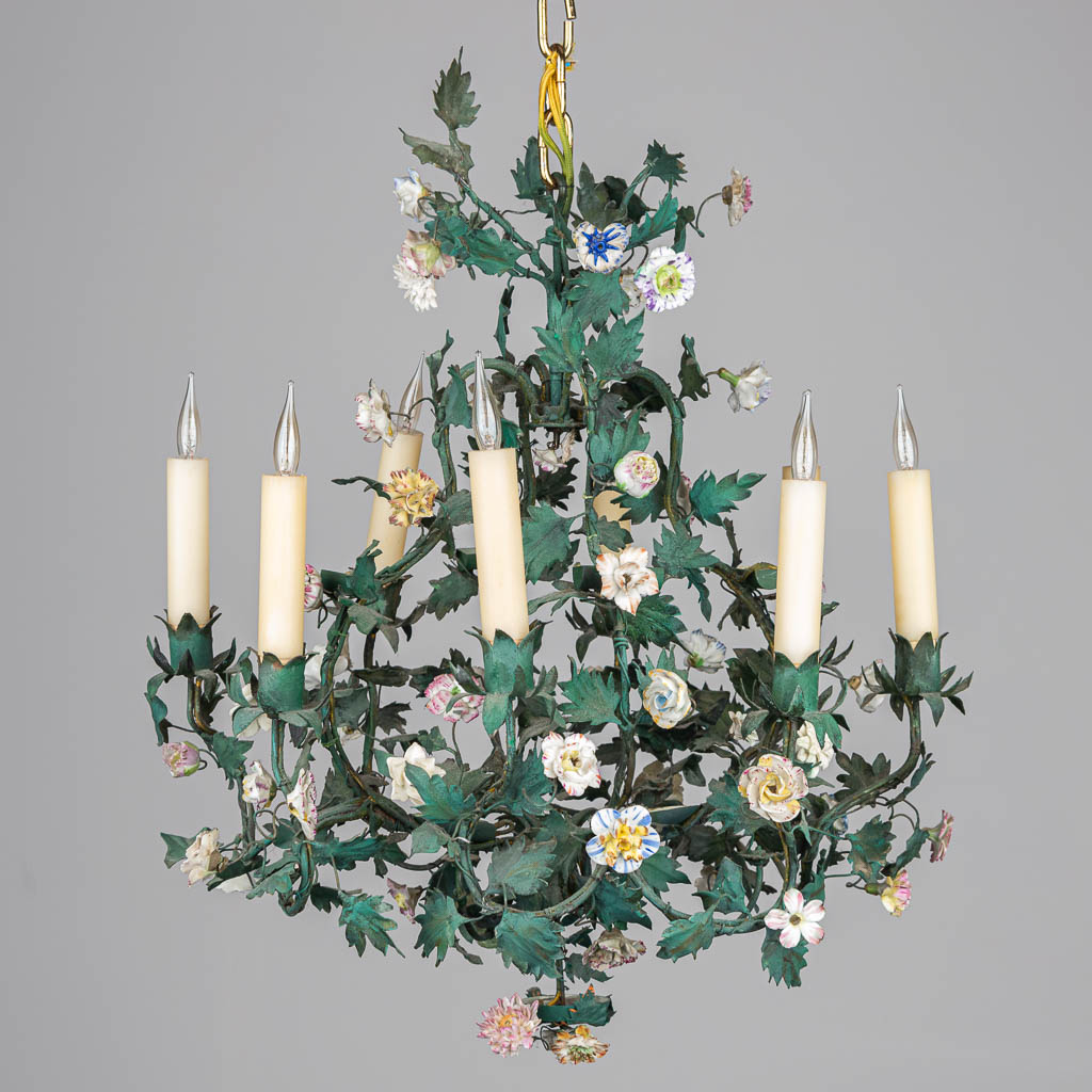 A chandelier made of metal and decorated with flowers made of porcelain. 