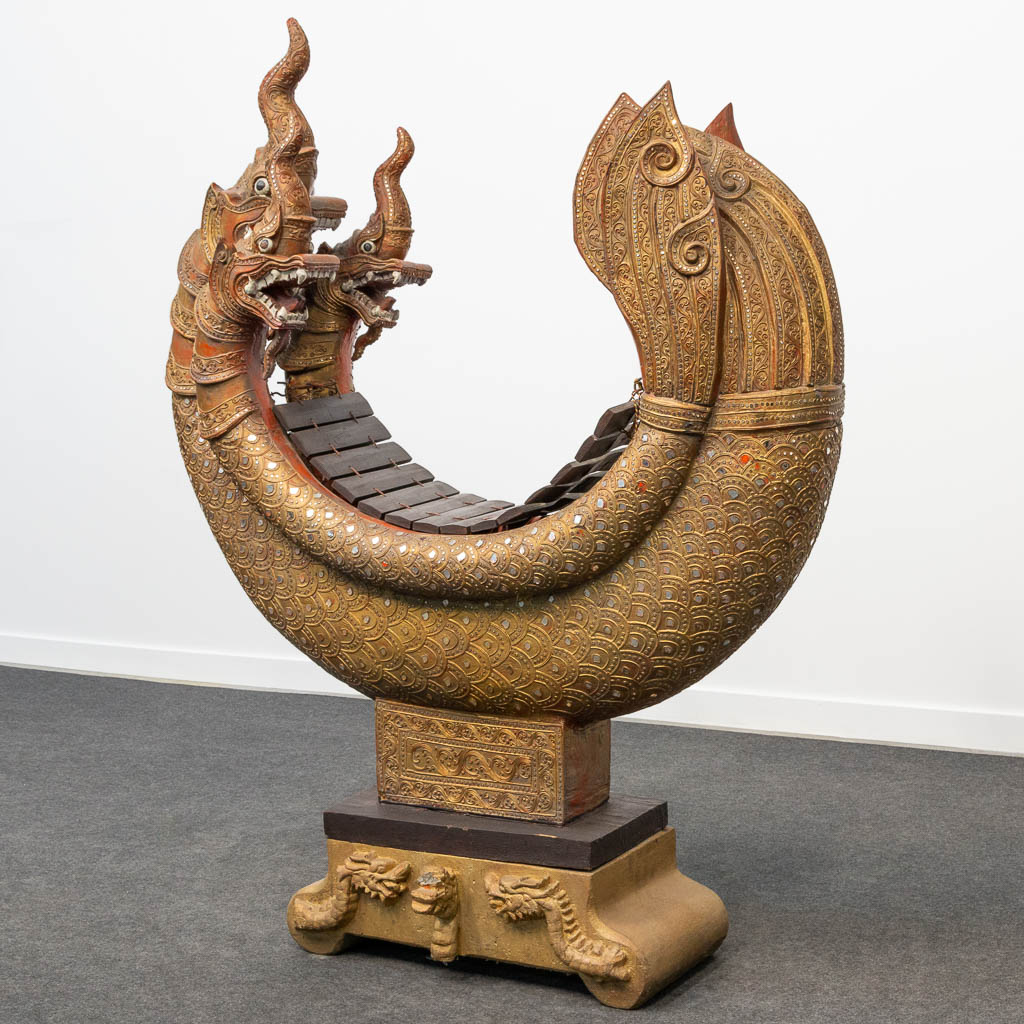 Een Xylofoon gemaakt uit gesculpteerd hout, in de vorm van een draak, op een basis gemaakt uit steen, Indonesië. (H:138cm)