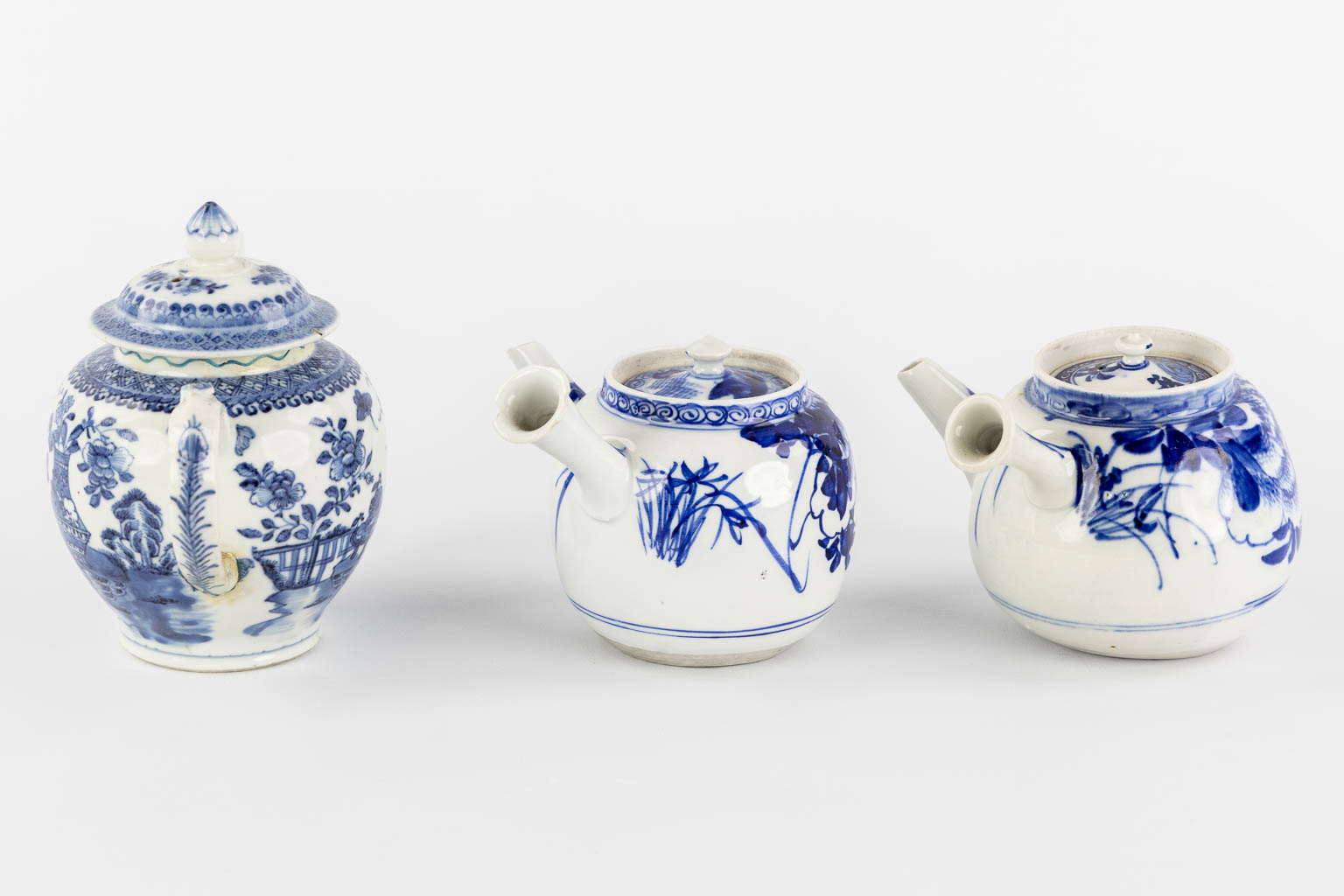 Three Chinese and Japanese teapots, blue-white decor. (W:20 x H:14 cm)