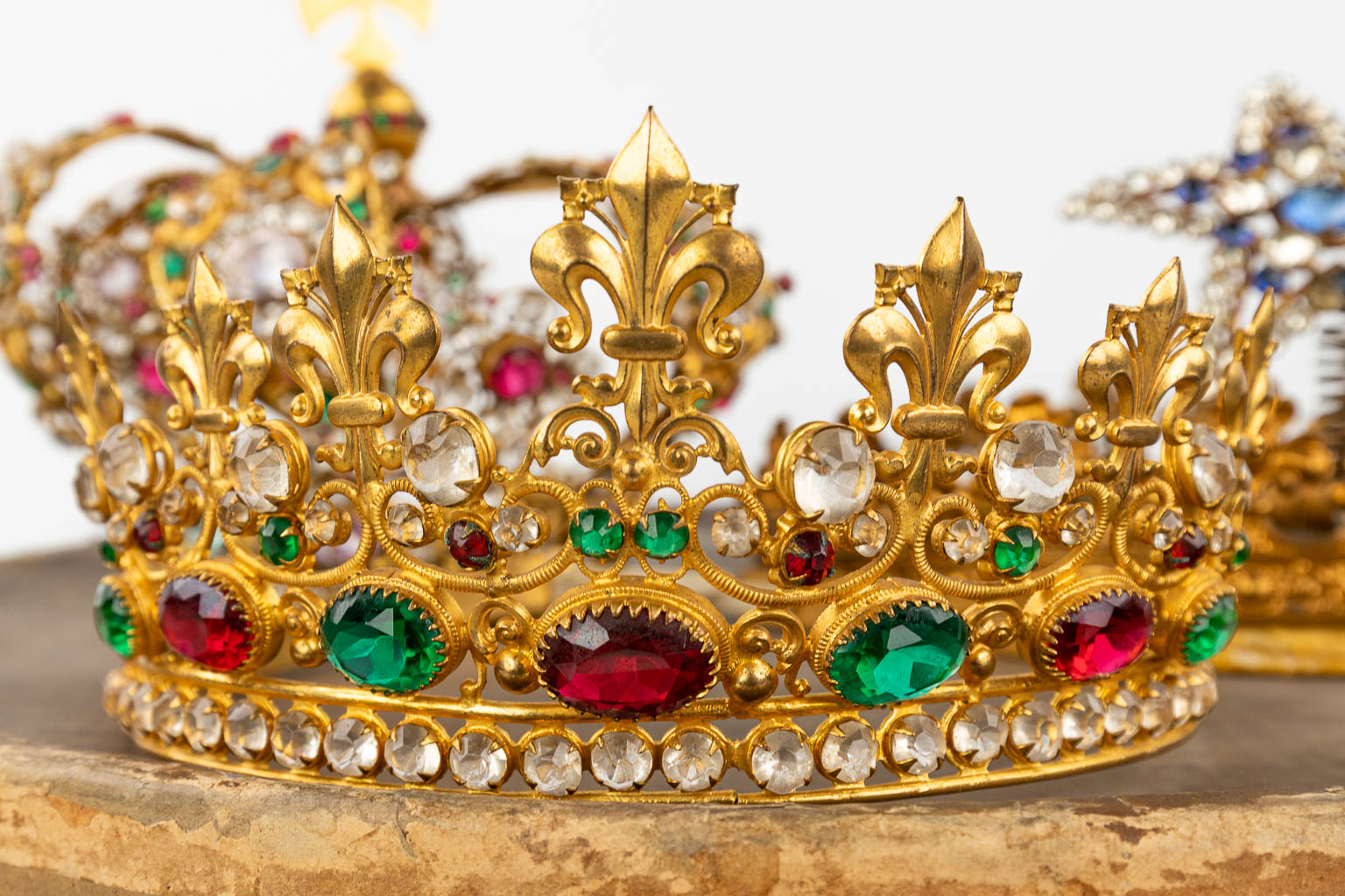 A large collection of big and small crowns for holy statues, and a staff. 
