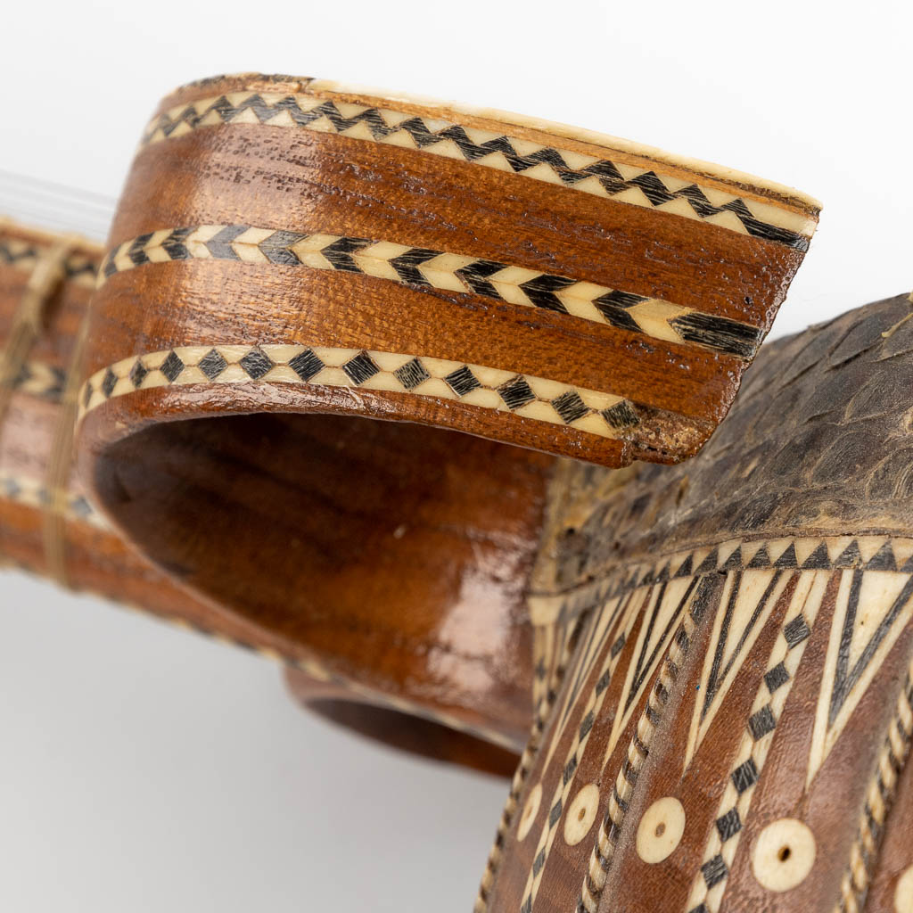 Een Oosters muziekinstrument met 6 snaren, slangenleder en ingelegd met been. 20ste eeuw. (D:13 x W:15 x H:93 cm)