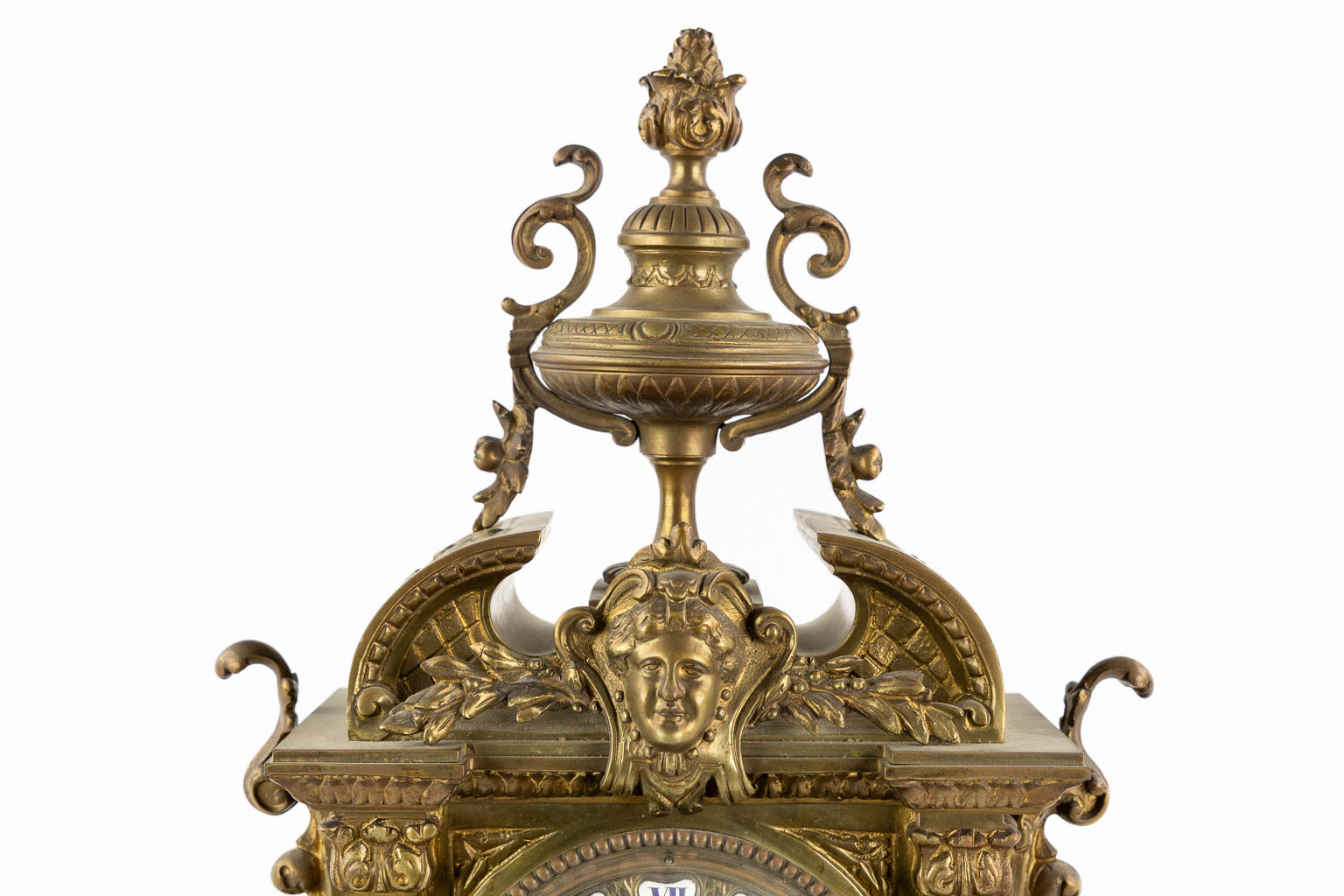 Een driedelige schouwgarnituur, klok met twee kandelaars. Gepatineerd brons. (L:16 x W:33 x H:50 cm)