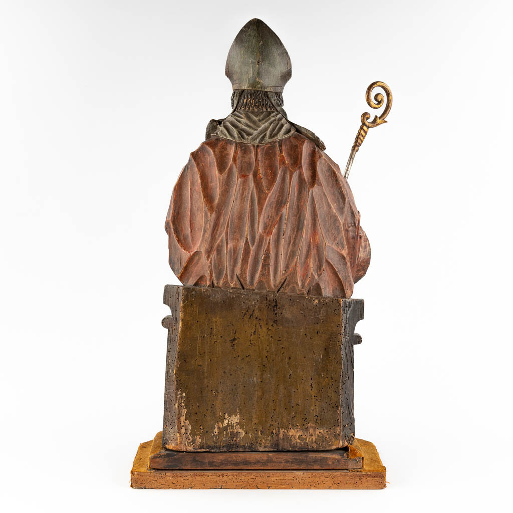 Een antieke houtsculptuur van een Heilige met staf en mijter, originele polychromie. 18de eeuw. (D:28 x W:38 x H:74 cm)