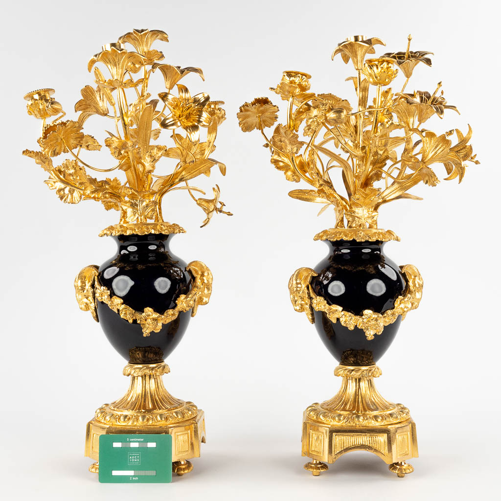 A pair of candelabra, gilt bronze on porcelain and decorated with flower decor. (D:30 x W:28 x H:53 cm)