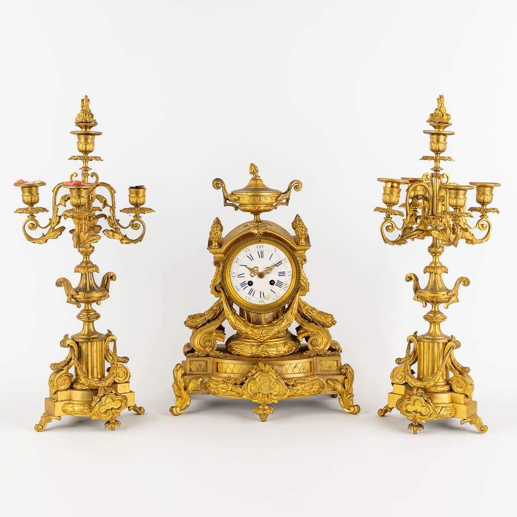A three-piece mantle garniture clock and candelabra, gilt bronze. 19th C. (L:20 x W:32 x H:43 cm)