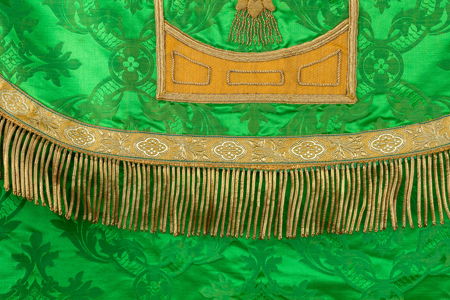 A Cope and Humeral Veil, finished with thick gold thread and green fabric and the IHS logo.