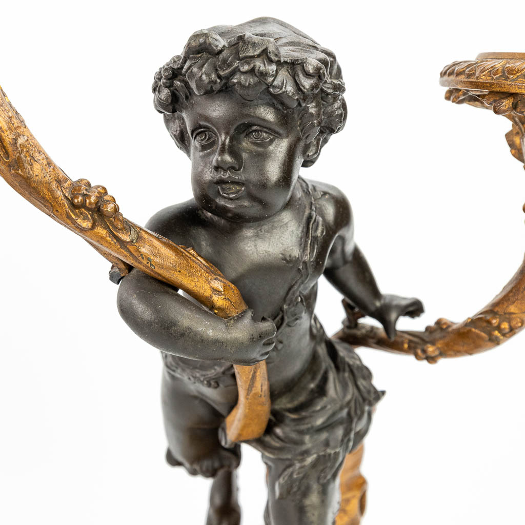 Een driedelige schouwgarnituur afgewerkt met putti en een satyr, gemaakt uit kunstbrons. (H:37cm)