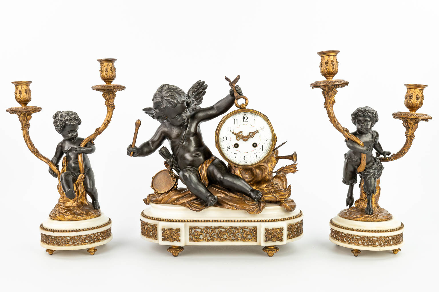 A three-piece mantle clock decorated with putti and a satyr, made of patinated and gilt spelter. (H:37cm)