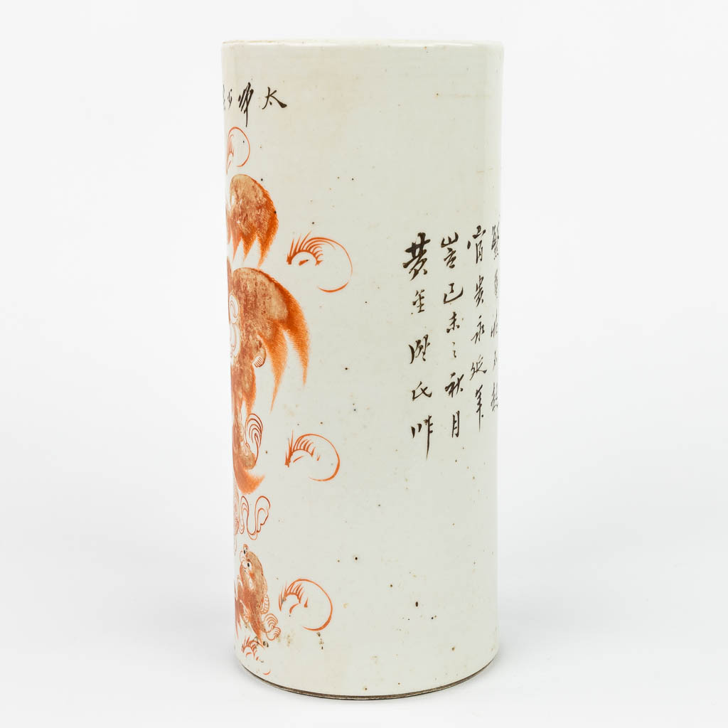 Een Chinese hoedensteun gemaakt uit porselein en versierd met rode foo hond. (H:27,5cm)