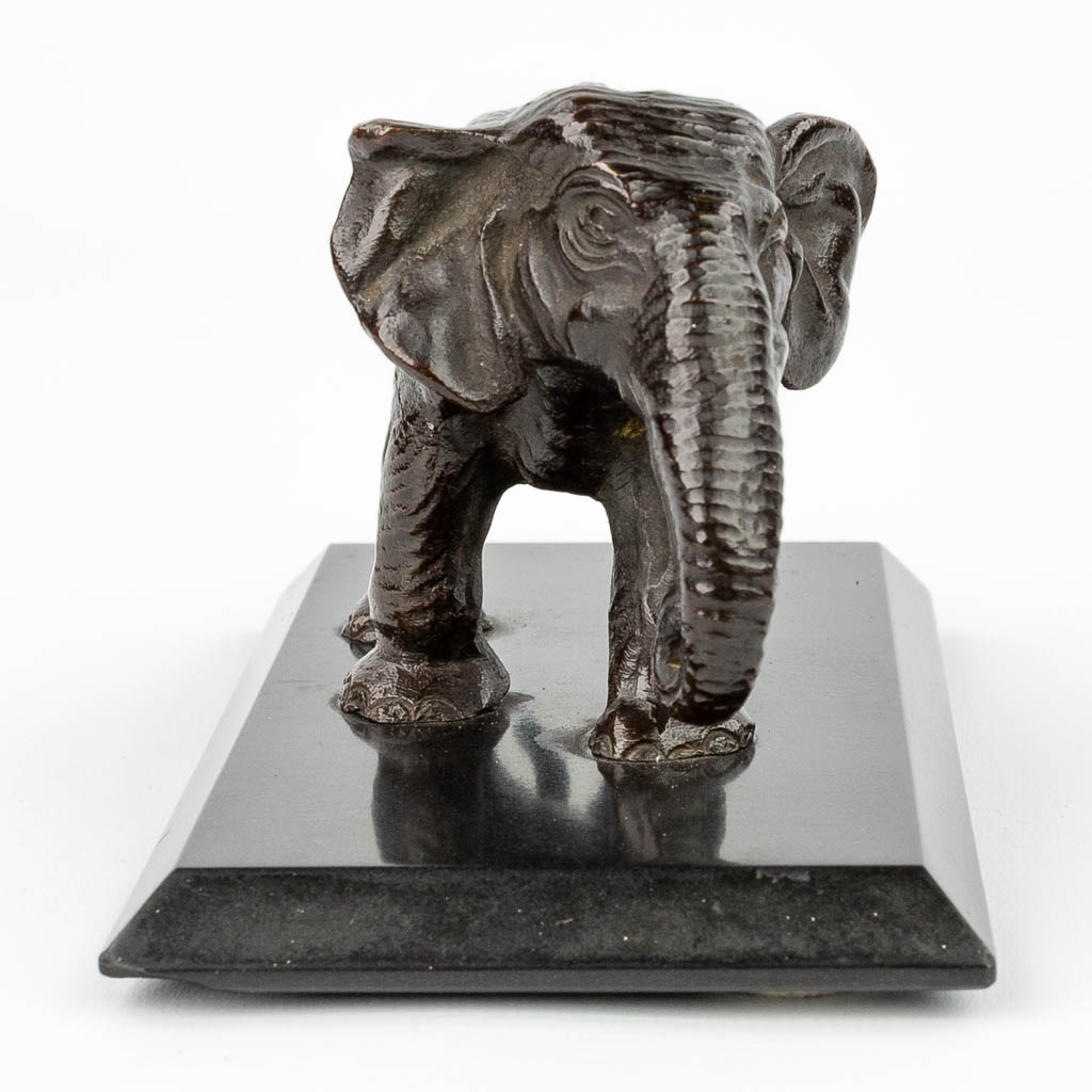 Een beeld van een olifant gemaakt uit brons en gemonteerd op een zwart marmer sokkel. (H:8cm)