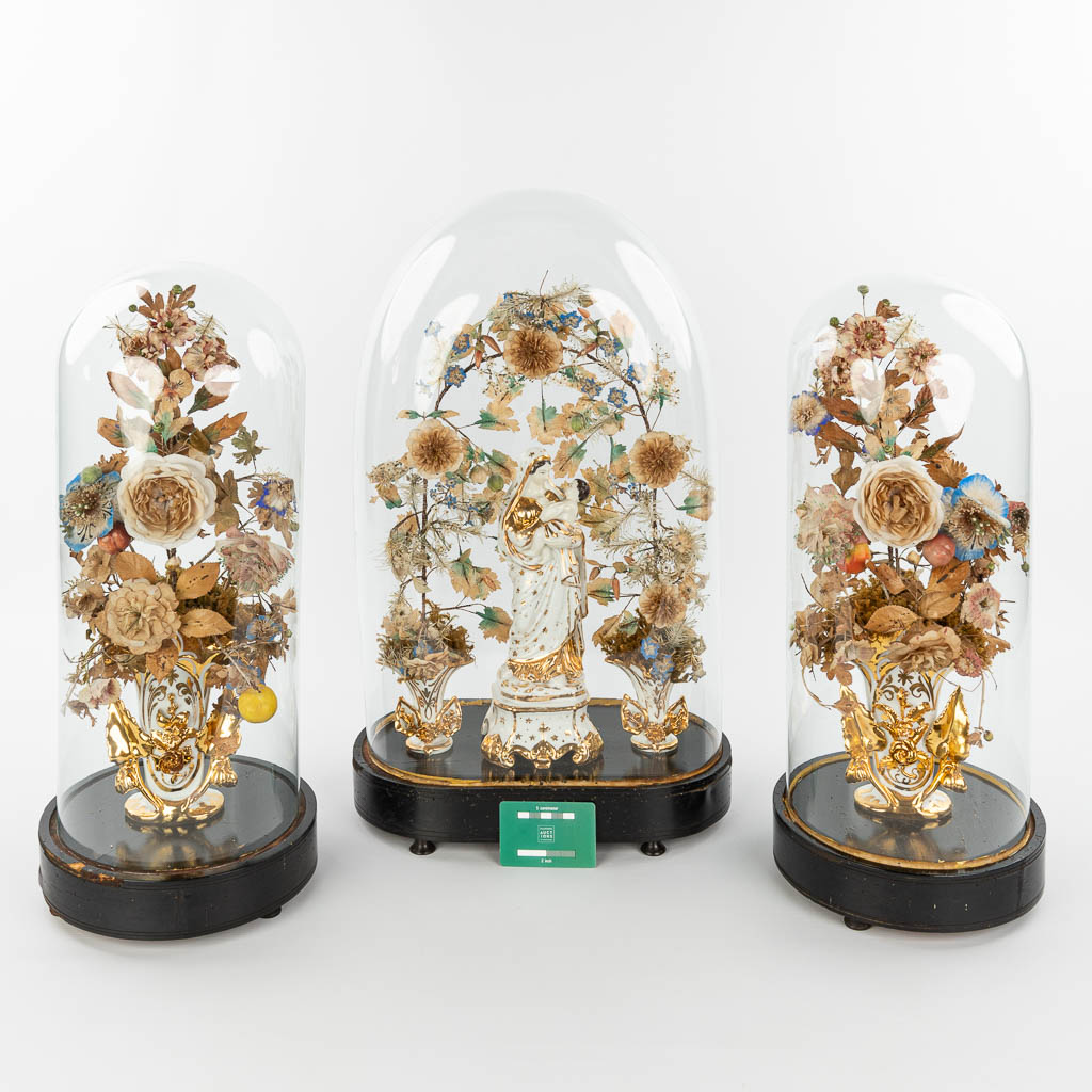Een driedelige schouwgarnituur met een collectie Vieux Bruxelles bloemenvazen en Madonna met kind onder globes. (H:60cm)